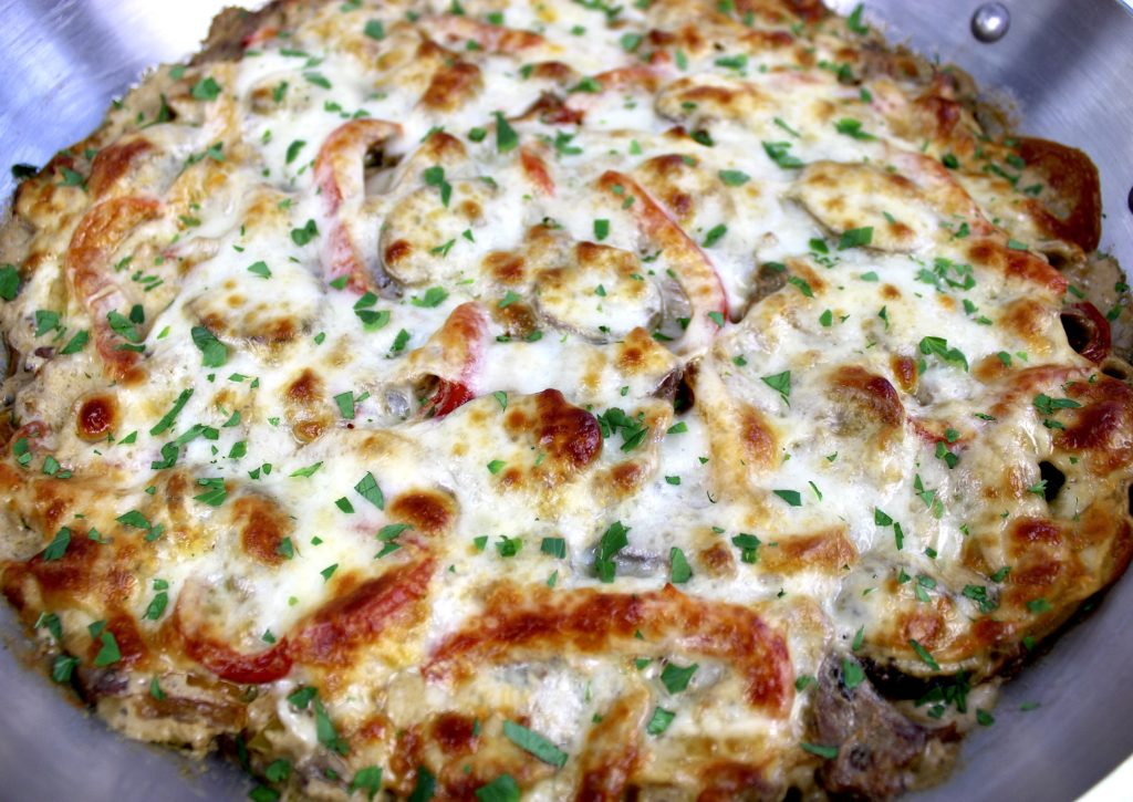 Philly Cheesesteak Casserole baked in skillet with chopped parsley over the top
