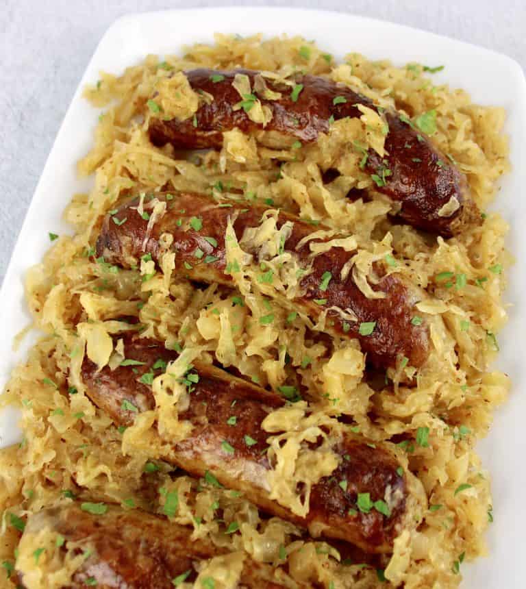 Kielbasa and Sauerkraut on white plate with parsley on top