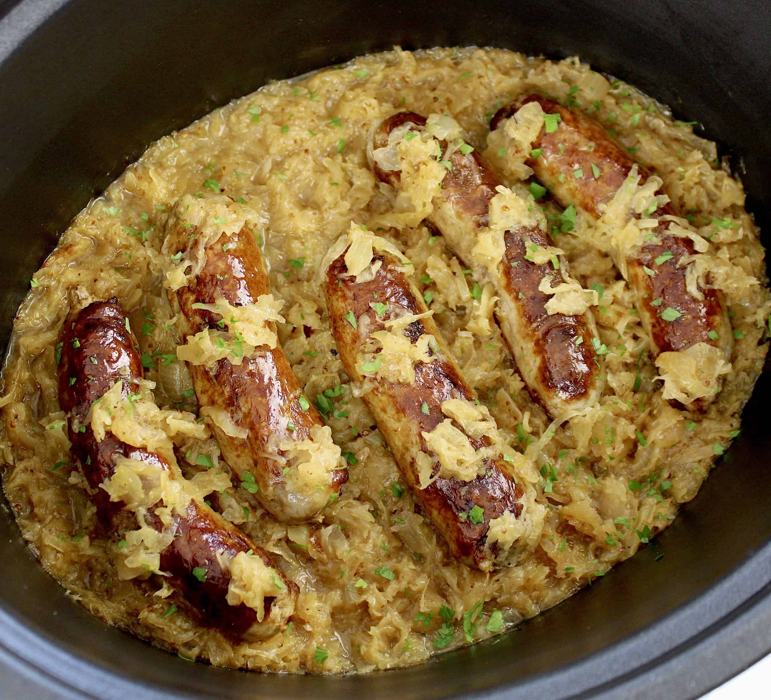 5 browned kielbasa on top of sauerkraut in slow cooker