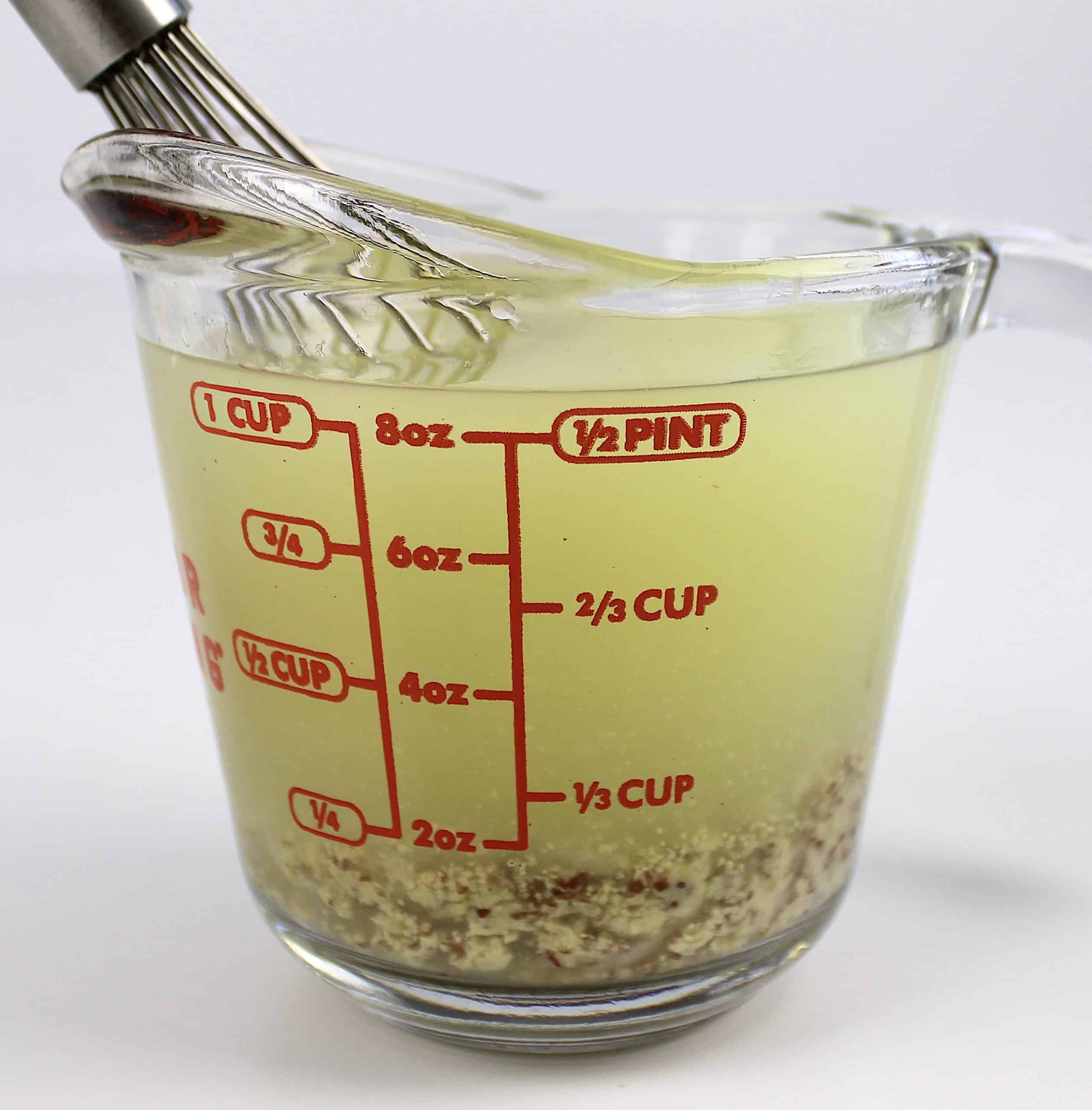 chicken broth and mustard in mixing cup with whisk
