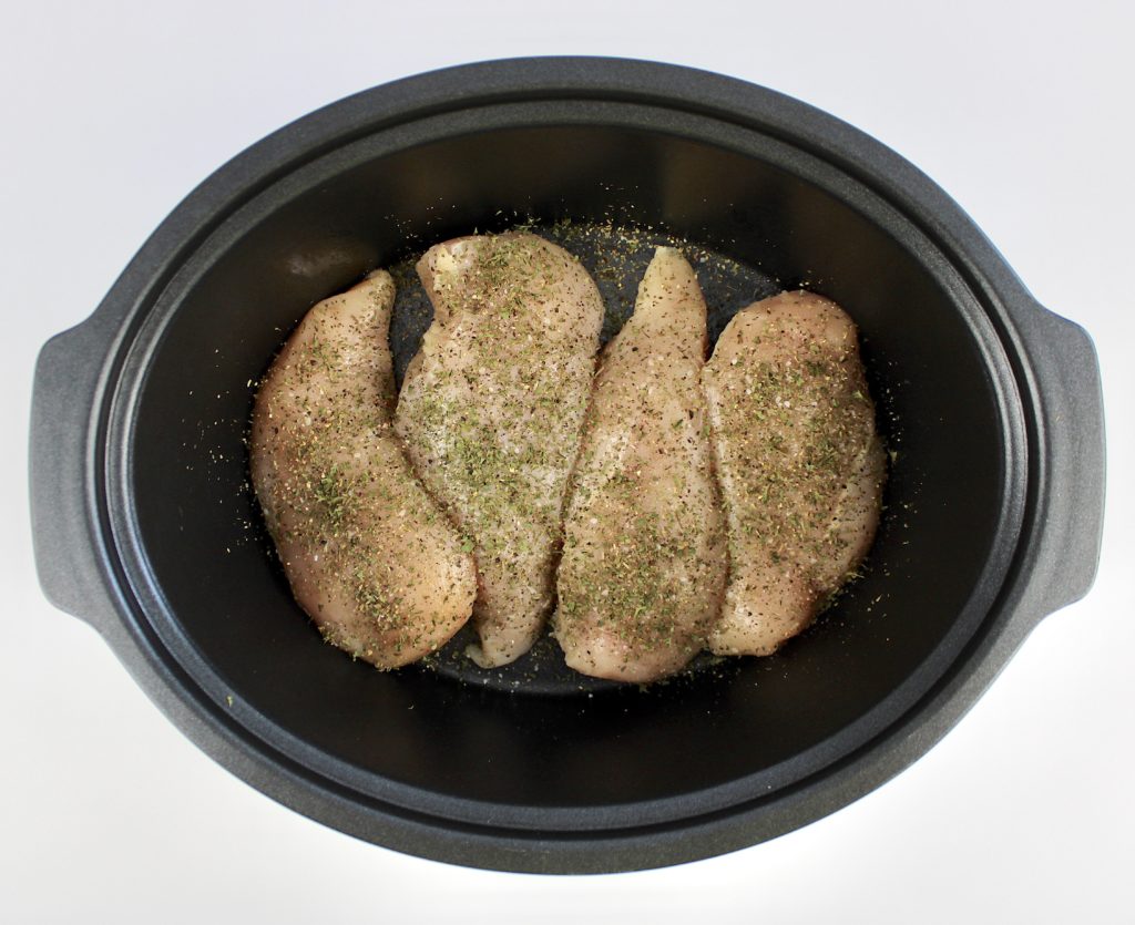4 chicken breasts in slow cooker with herbs on top