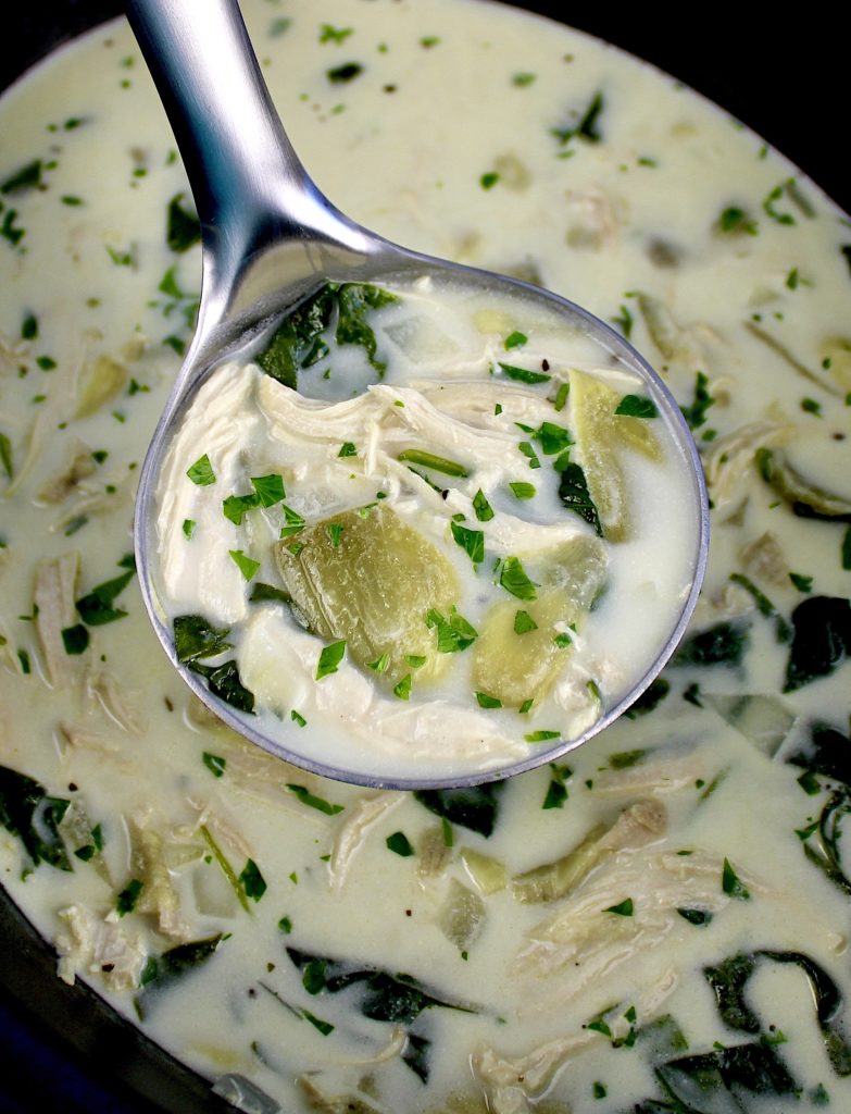 spinach artichoke chicken soup being ladled from slow cooker