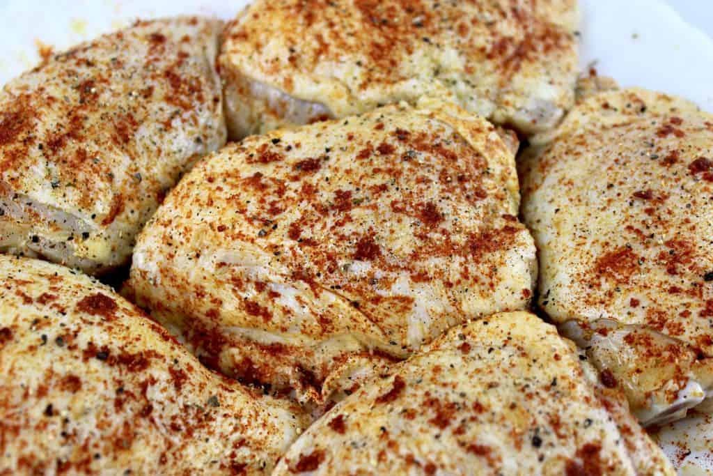 closeup of raw chicken thighs with spices on top