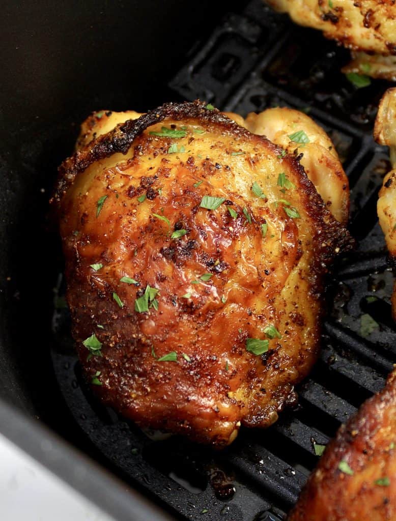 closeup of cooked chicken thighs in air fryer basket