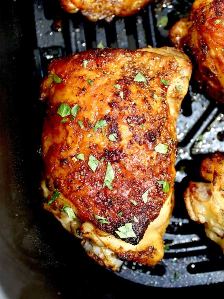 closeup of cooked chicken thigh in air fryer basket