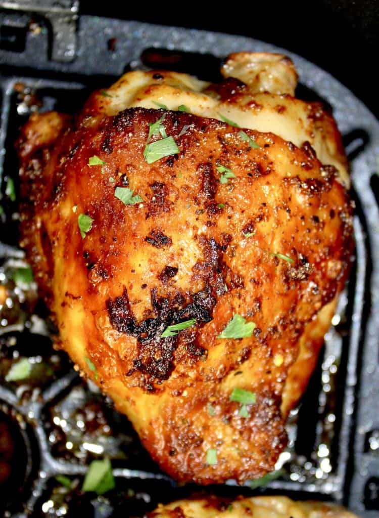 closeup of cooked chicken thigh in air fryer basket