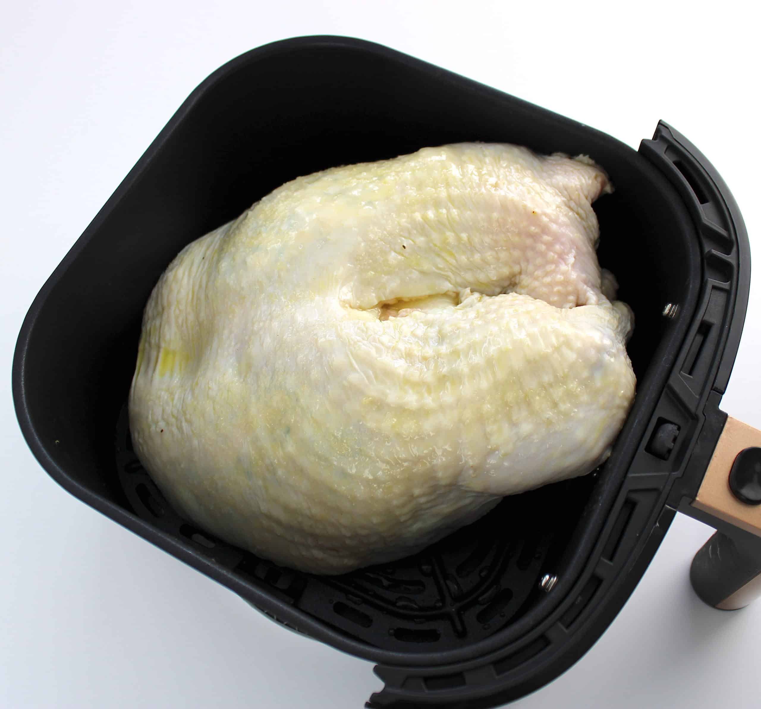 raw turkey breast with olive oil in air fryer basket