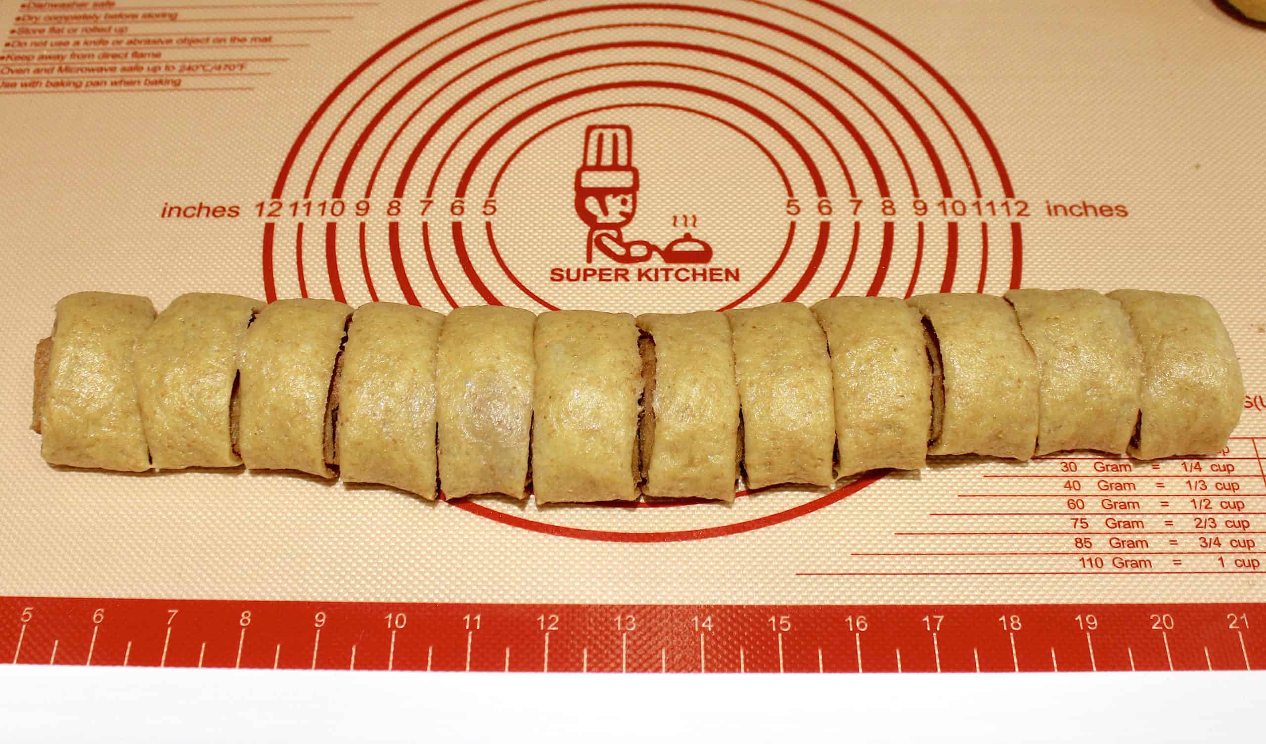 log of cinnamon roll dough cut into 12 pieces on silpat