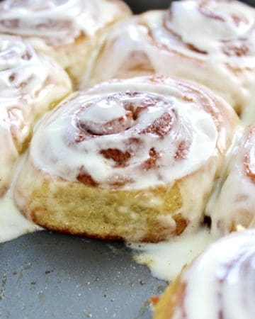 closeup of cinnamon rolls in pan with icing