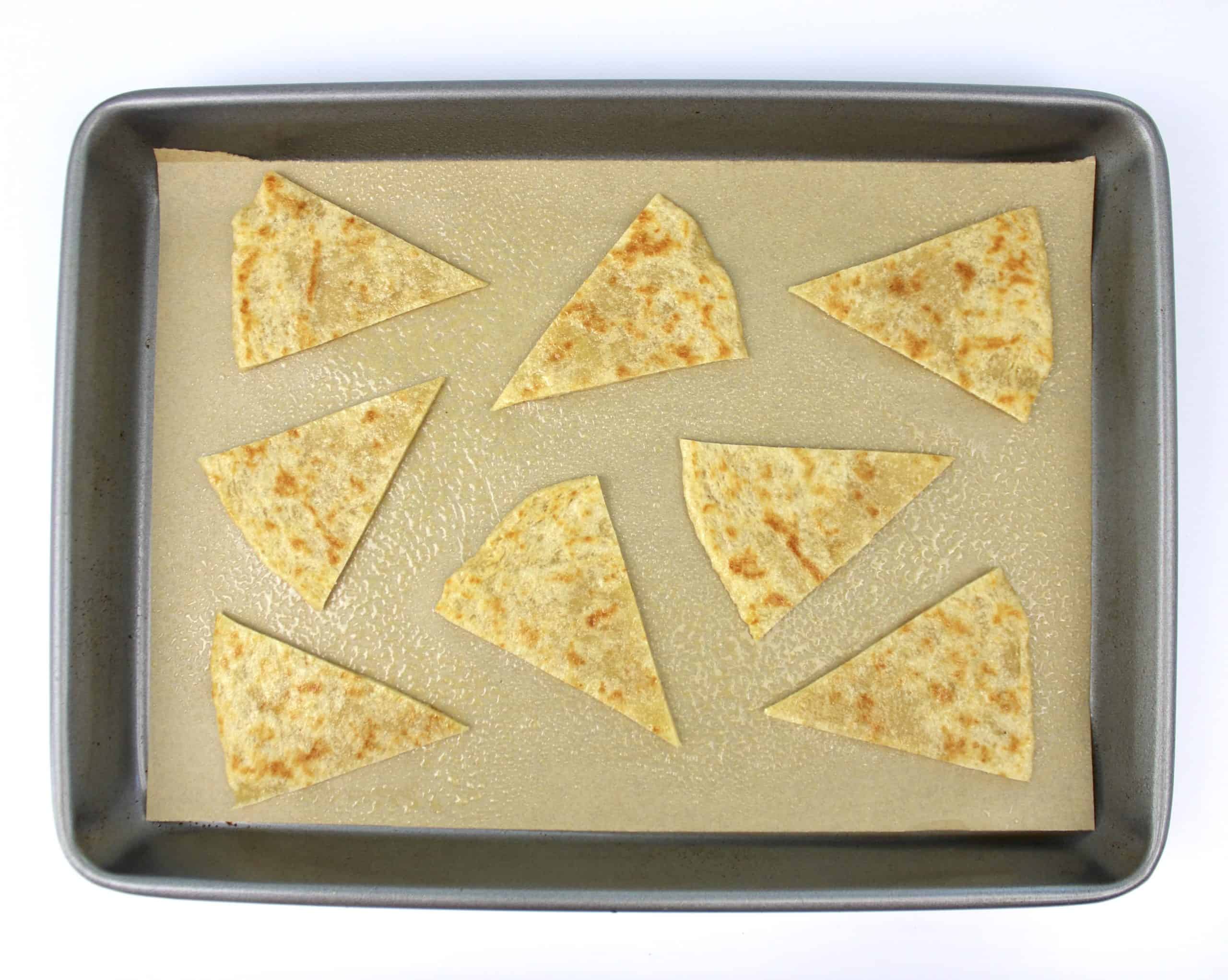 8 tortilla chips on baking sheet with parchment unbaked