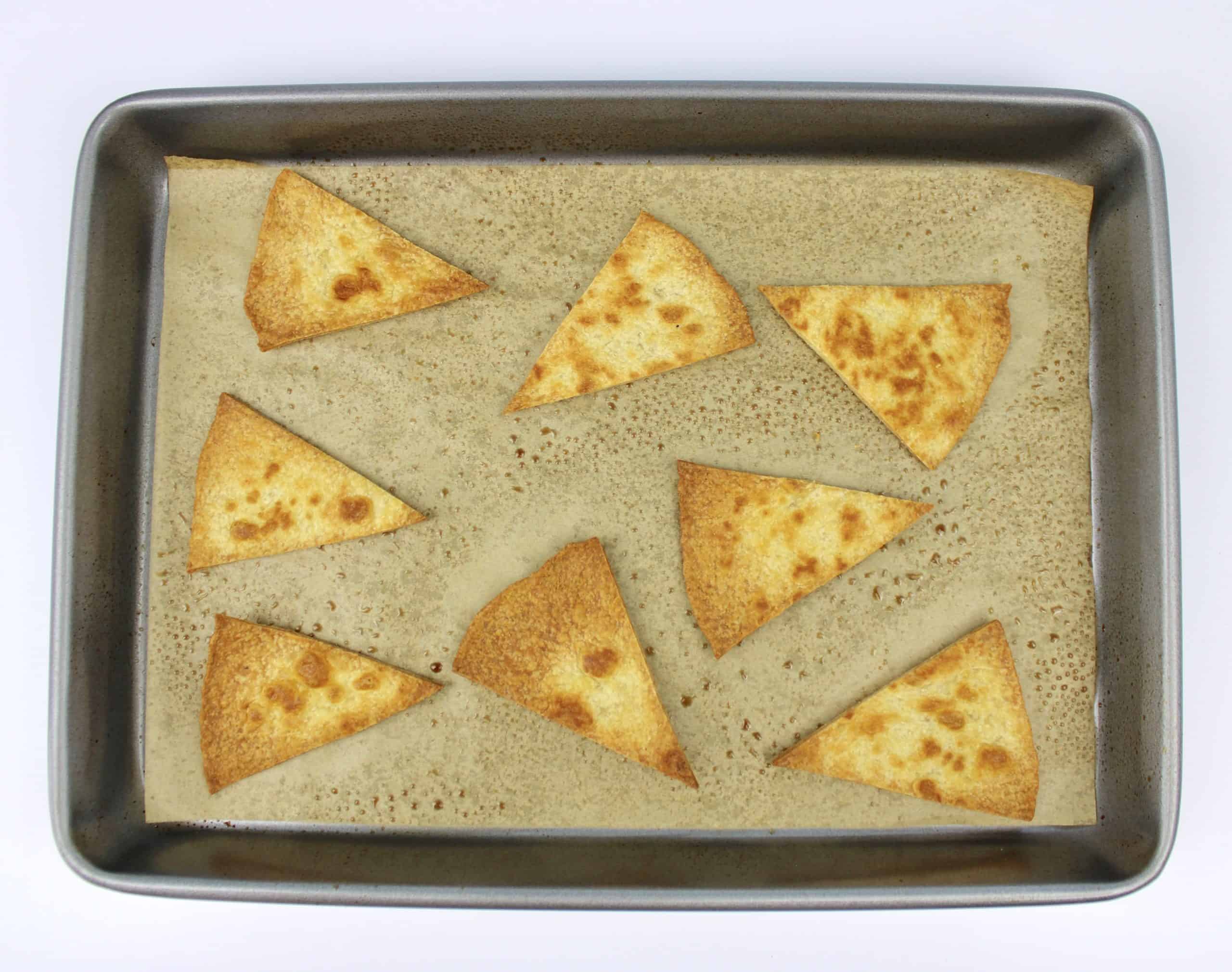8 tortilla chips on baking sheet with parchment unbaked
