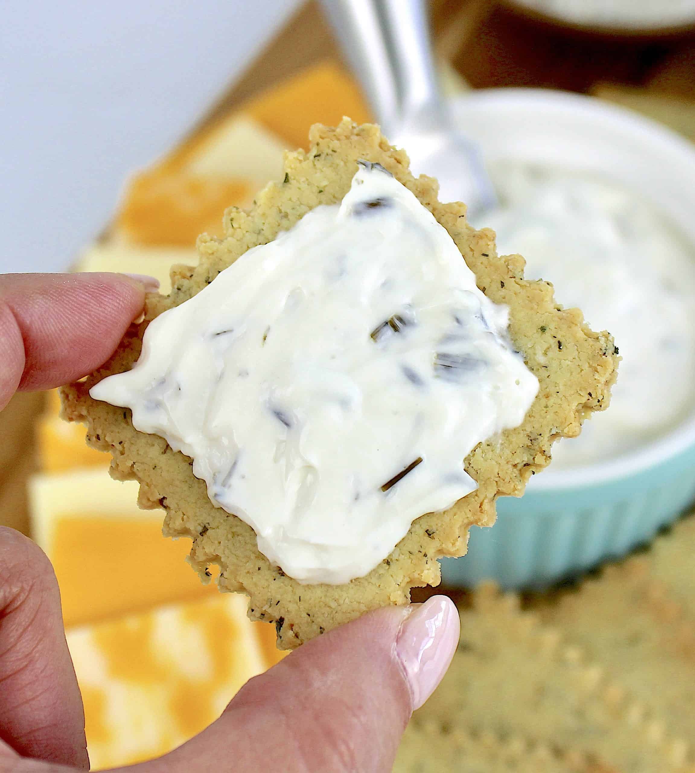 holding up ranch cracker with chive spread on top