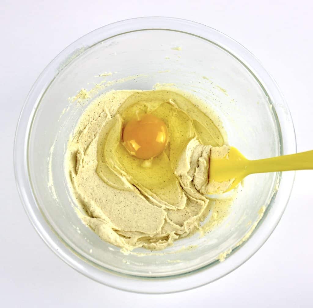 butter mixture with raw egg in glass bowl and yellow spoon