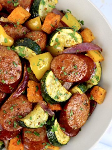 bowl of roasted veggies and sausage in beige bowl
