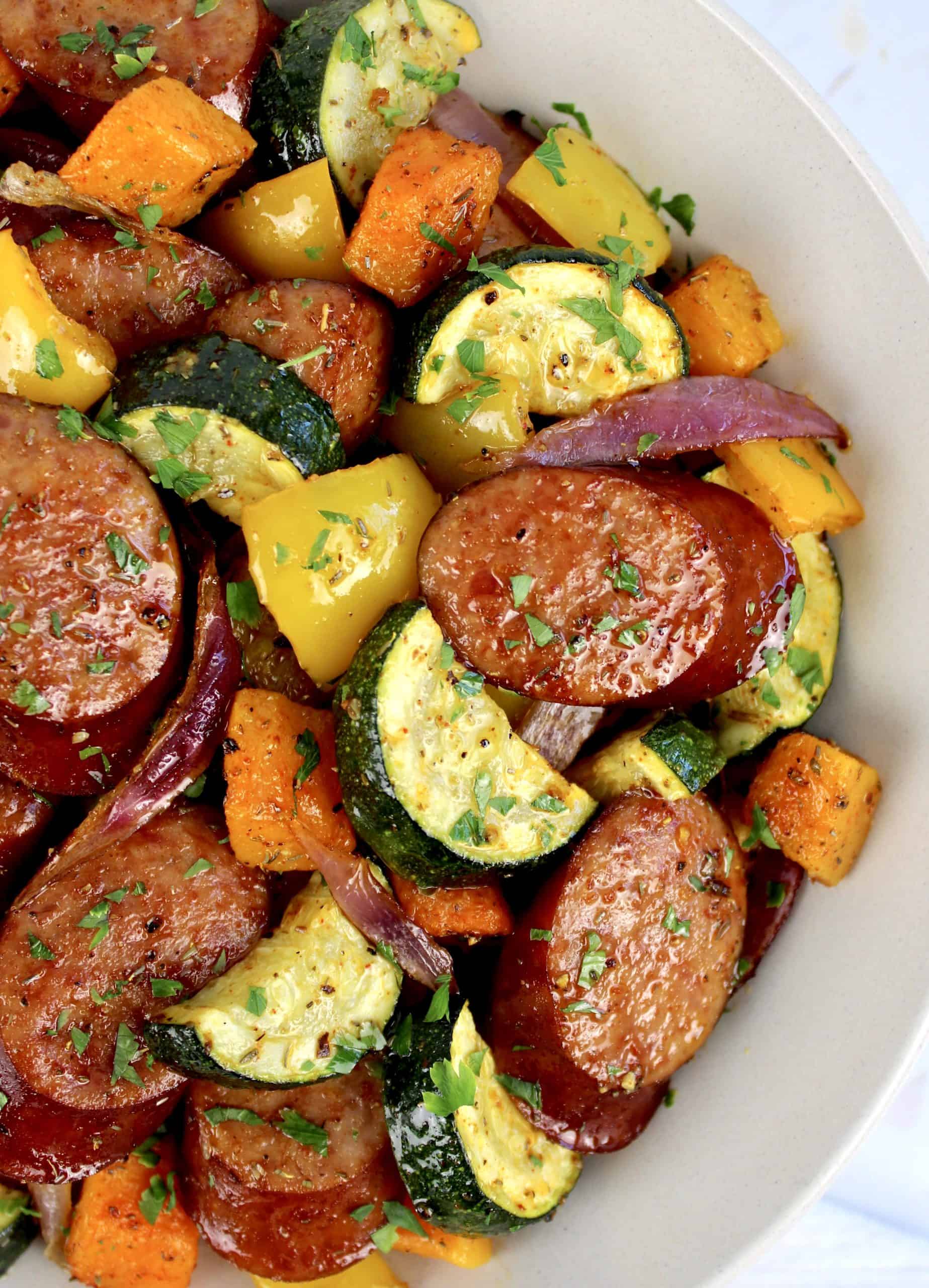 bowl of roasted veggies and sausage in beige bowl