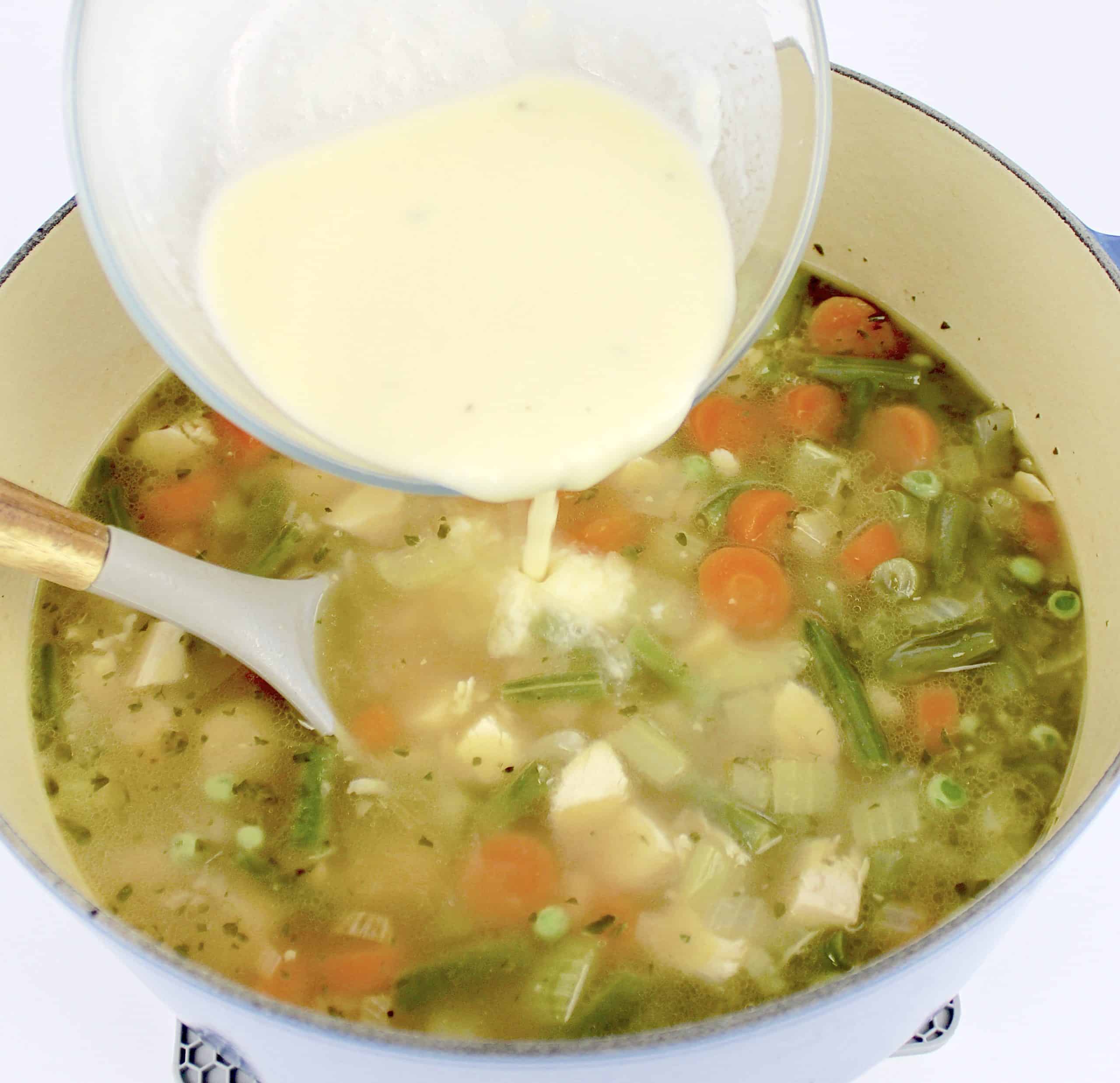 cream being poured into chicken soup