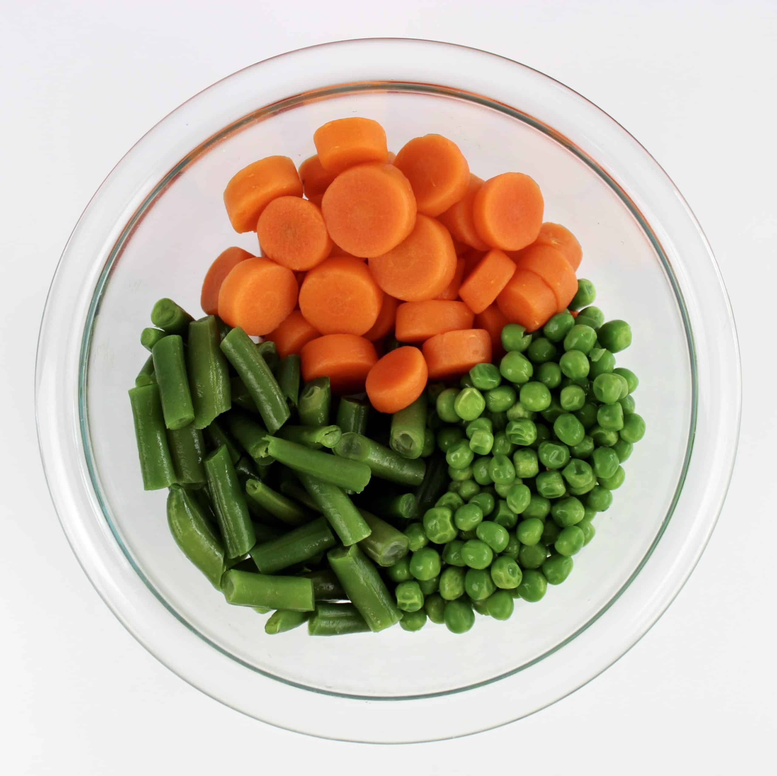 peas carrots green beans in glass bowl
