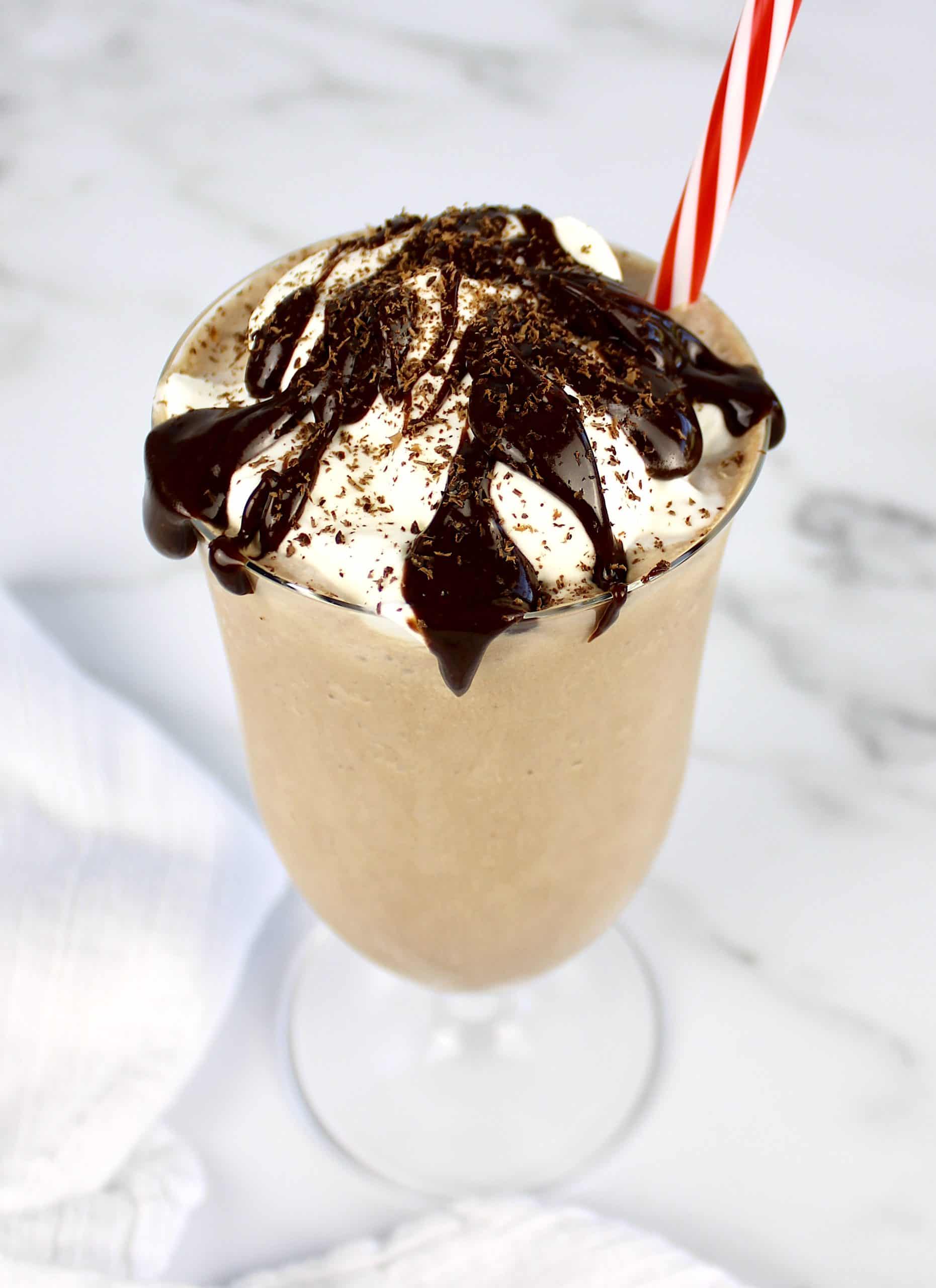 chocolate milkshake in glass with whip cream and chocolate sauce on top