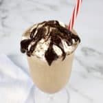 chocolate milkshake in glass with whip cream and chocolate sauce on top