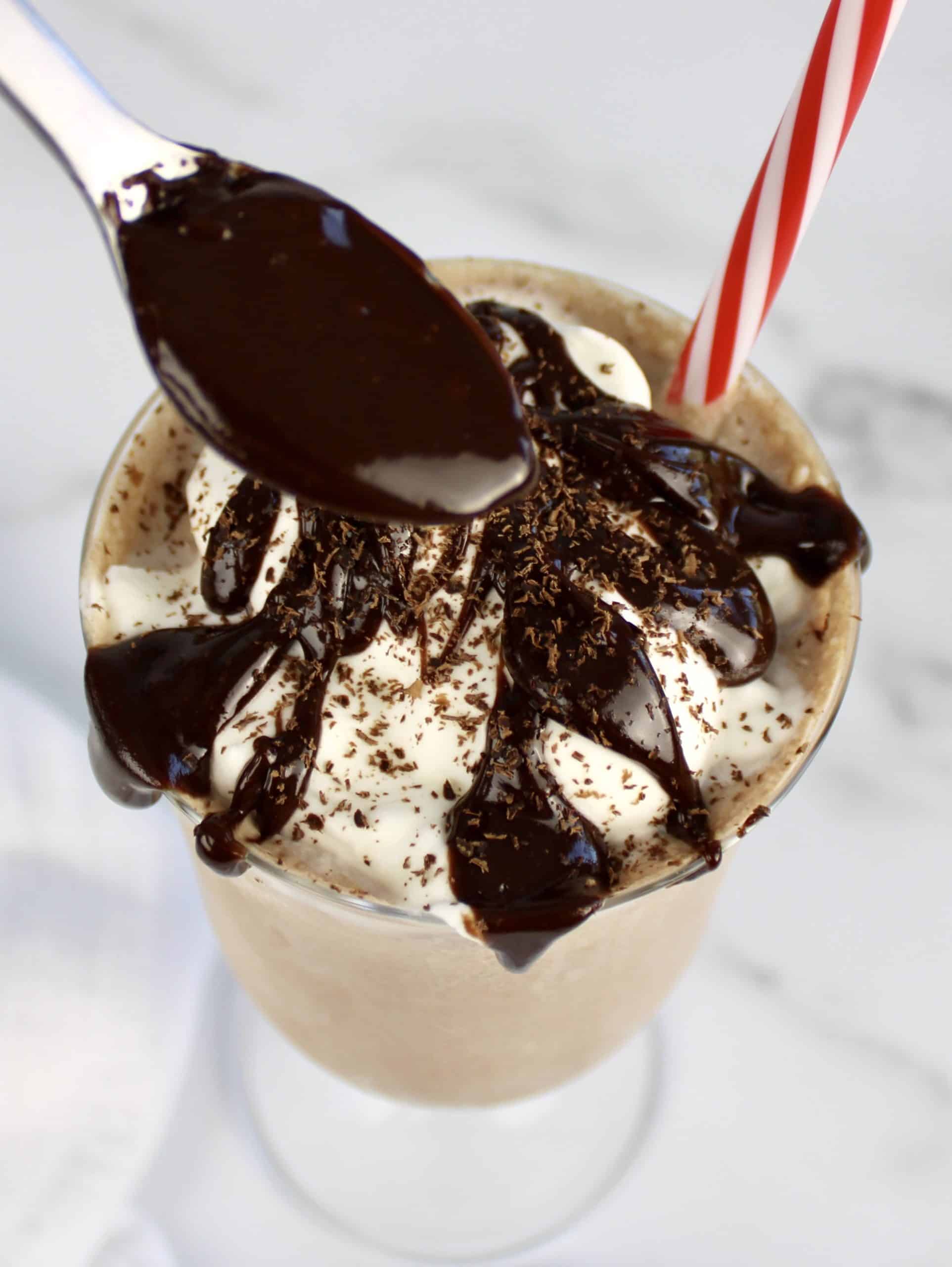 closeup of chocolate milkshake with chocolate being spooned over top