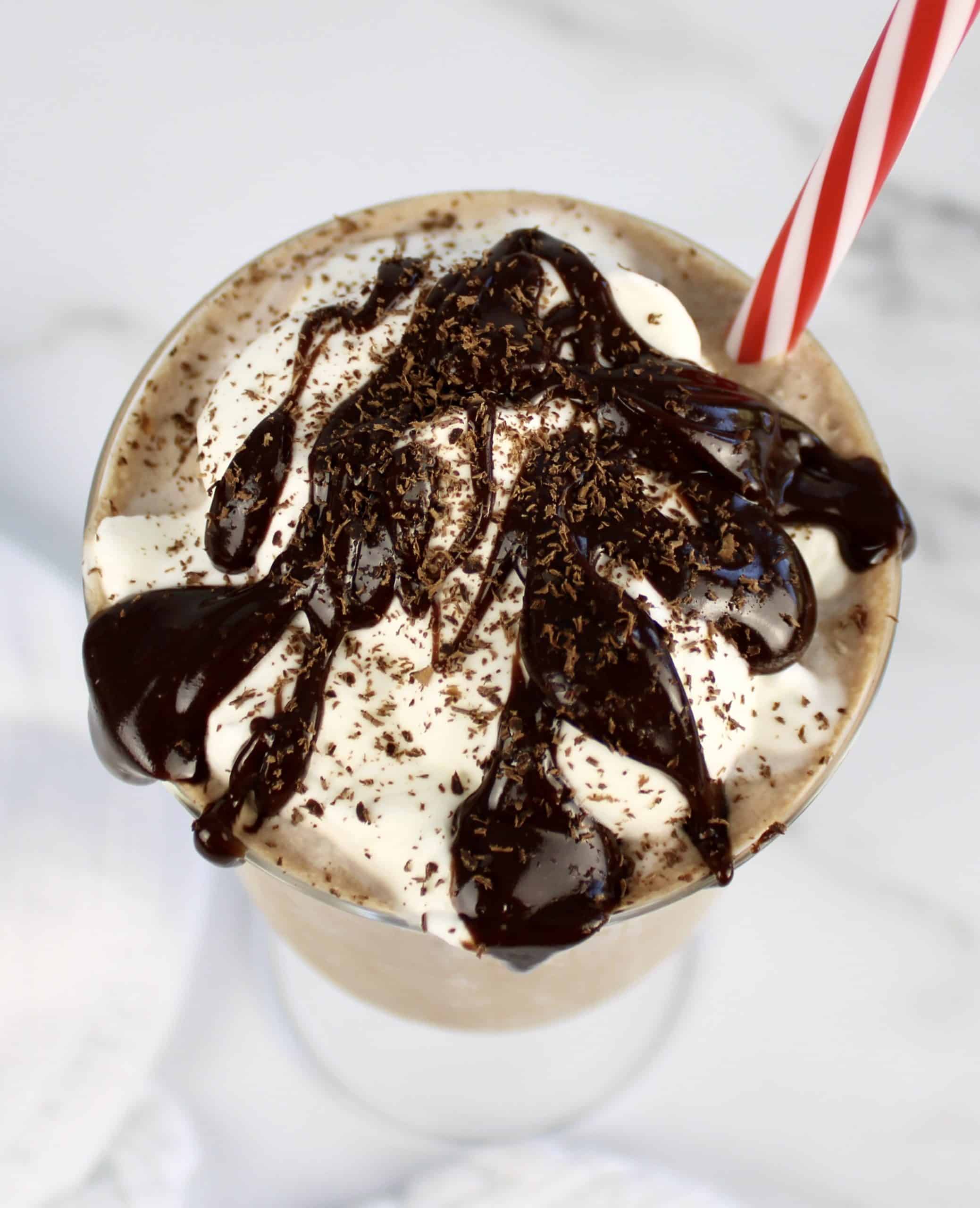 chocolate milkshake in glass with whip cream and chocolate sauce on top