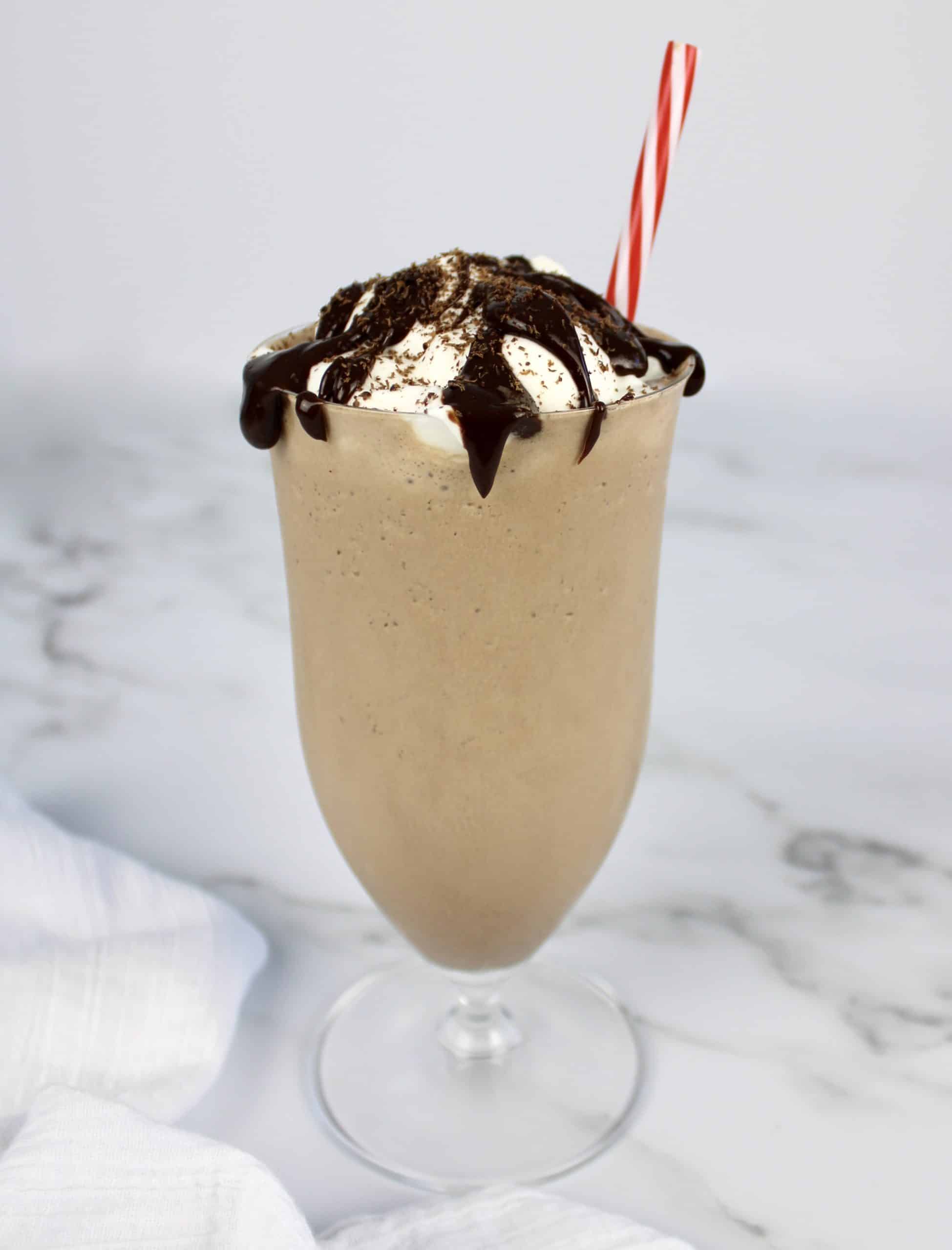 side view of chocolate milkshake with whip cream and chocolate sauce on top