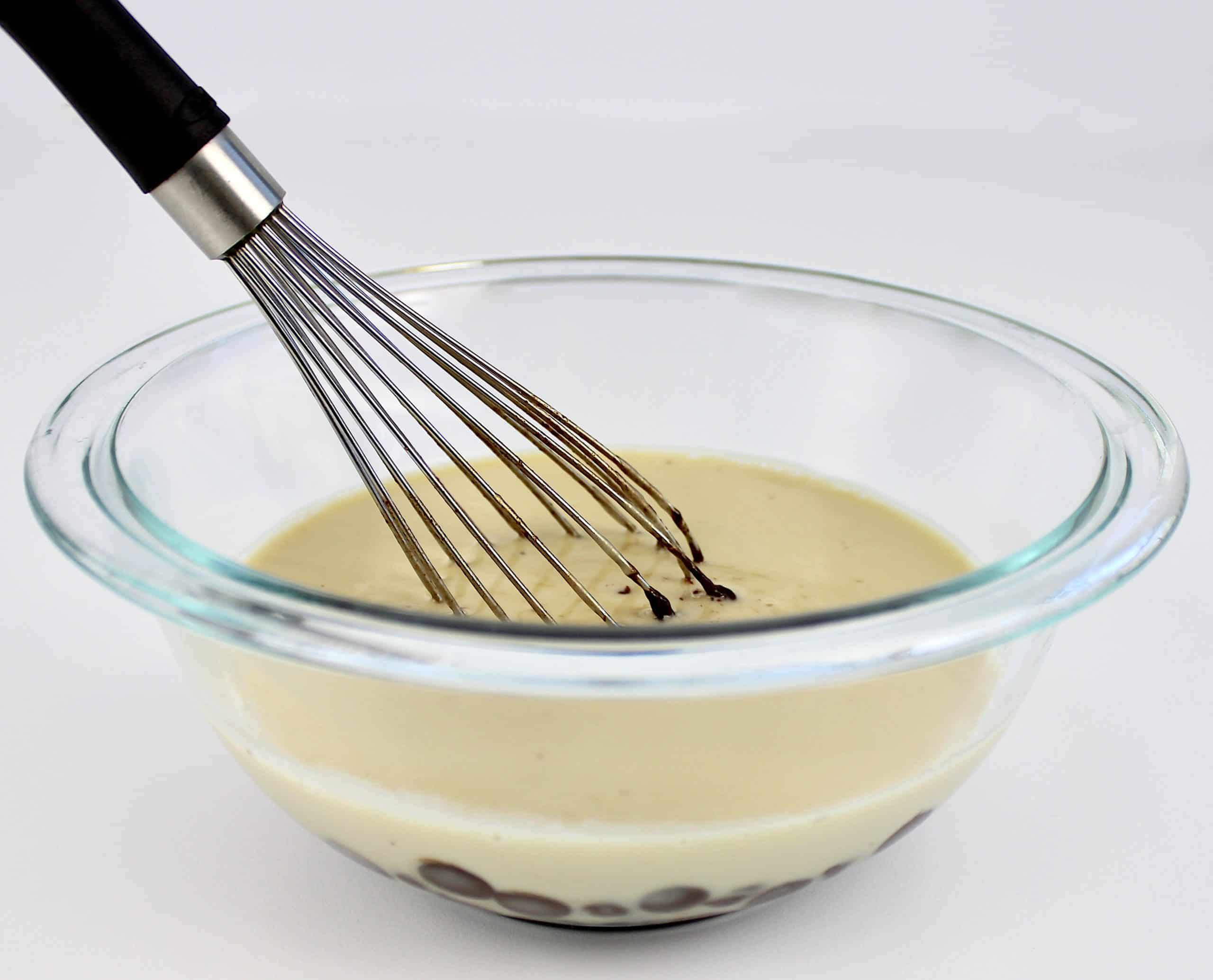 cream and chocolate chips in glass bowl with whisk