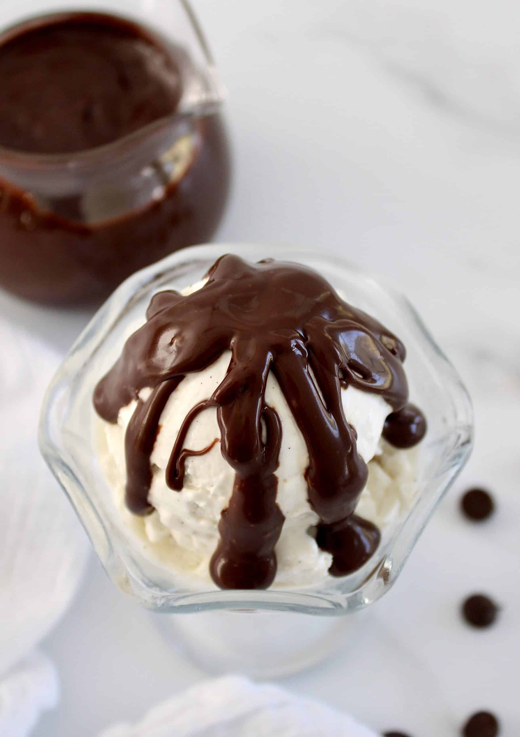 overhead view of ice cream in glass dish with chocolate sauce drizzled over top
