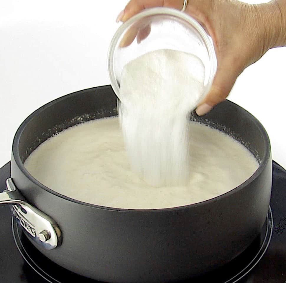 sweetener being poured into cream in saucepan