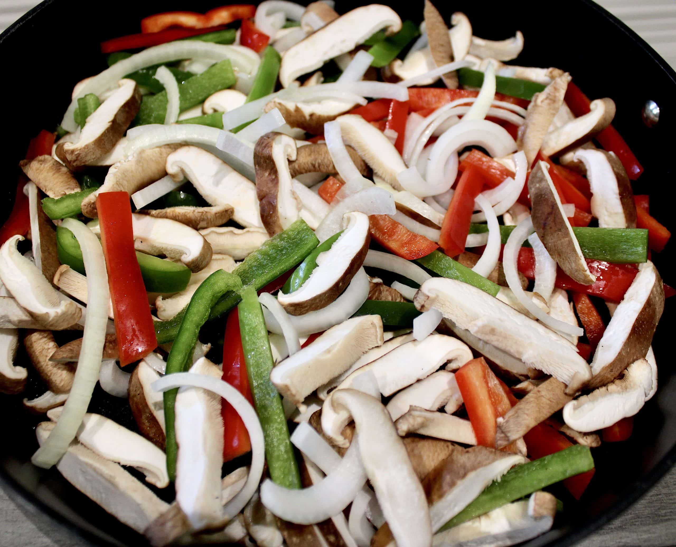 sliced onions peppers and mushrooms raw in skillet
