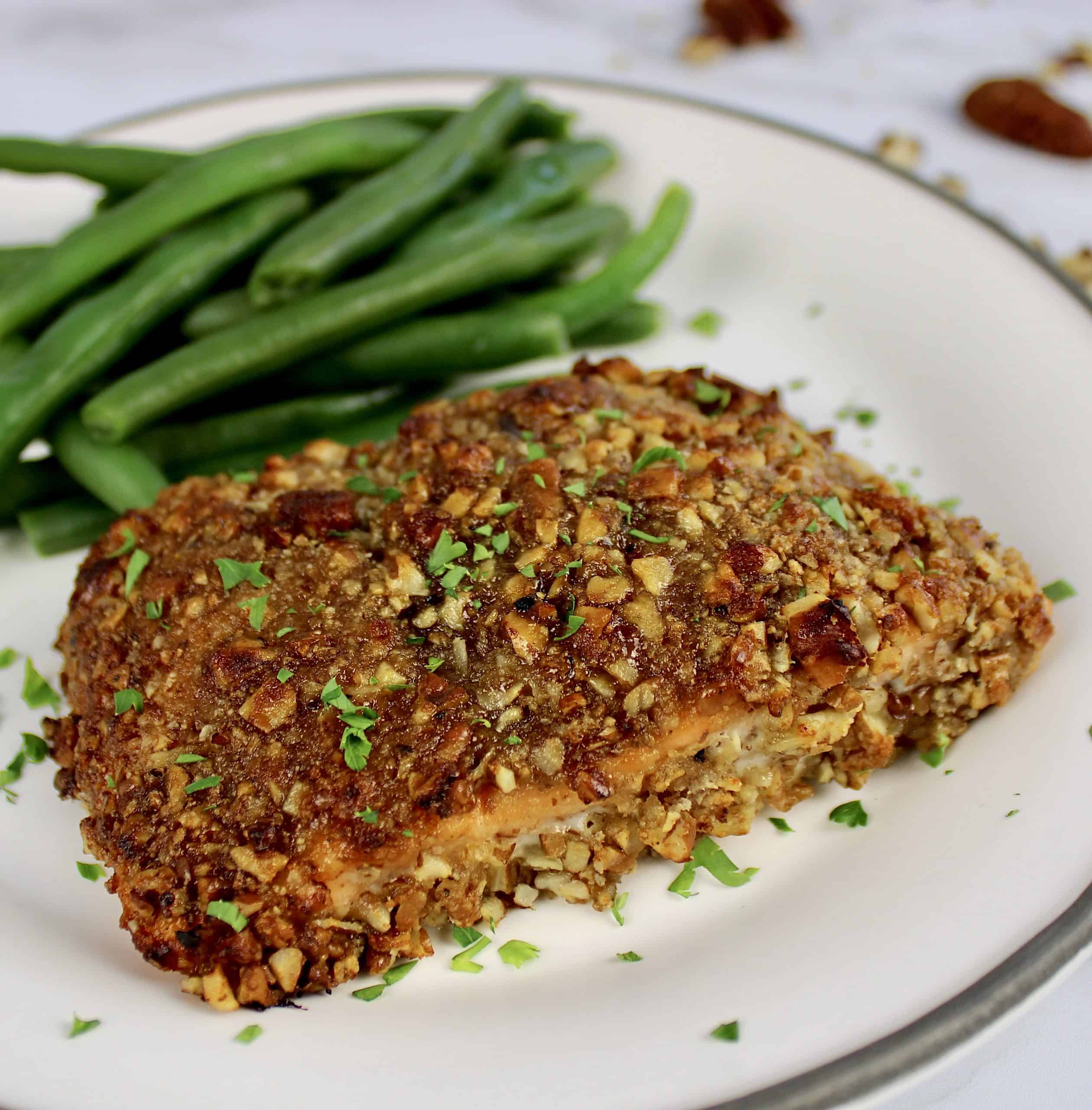 side view of Pecan Crusted Salmon on white plate with green beans