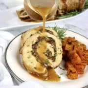 Stuffed Pork Loin with gravy being poured over top and butternut squash on side