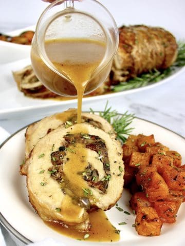 Stuffed Pork Loin with gravy being poured over top and butternut squash on side