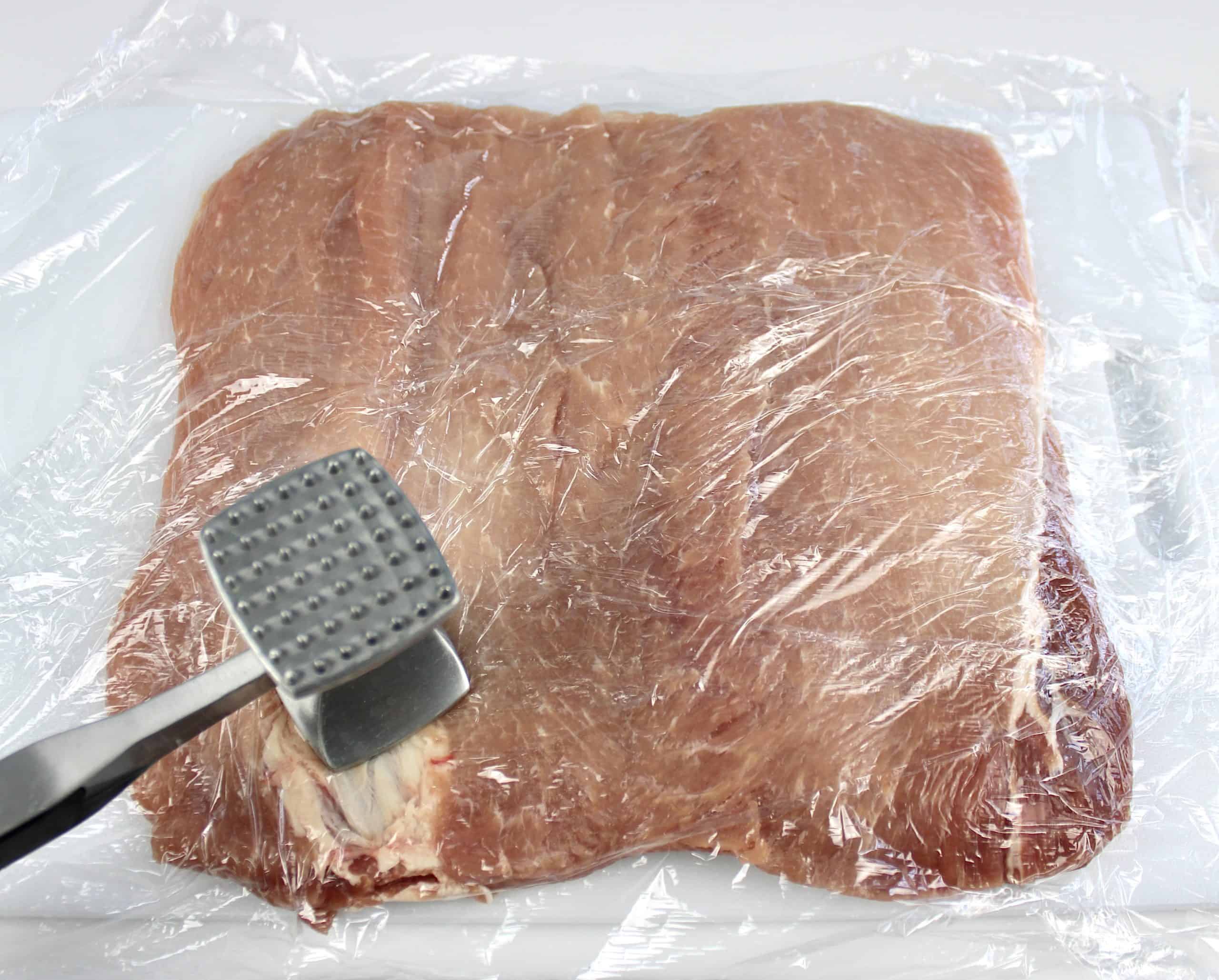 pork loin with plastic wrap and meat mallet