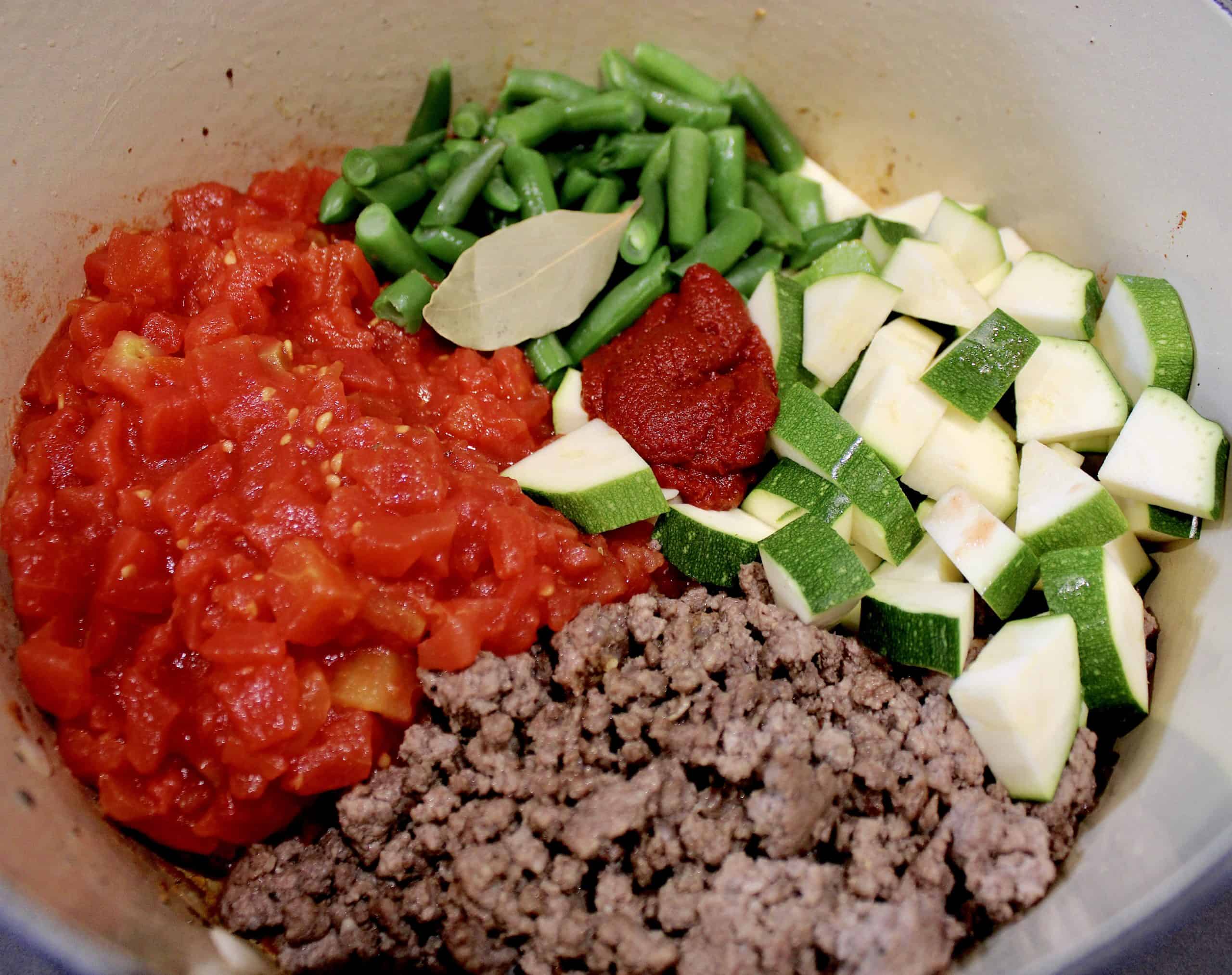 tomatoes chopped zucchini green beans and ground beef in pot uncooked