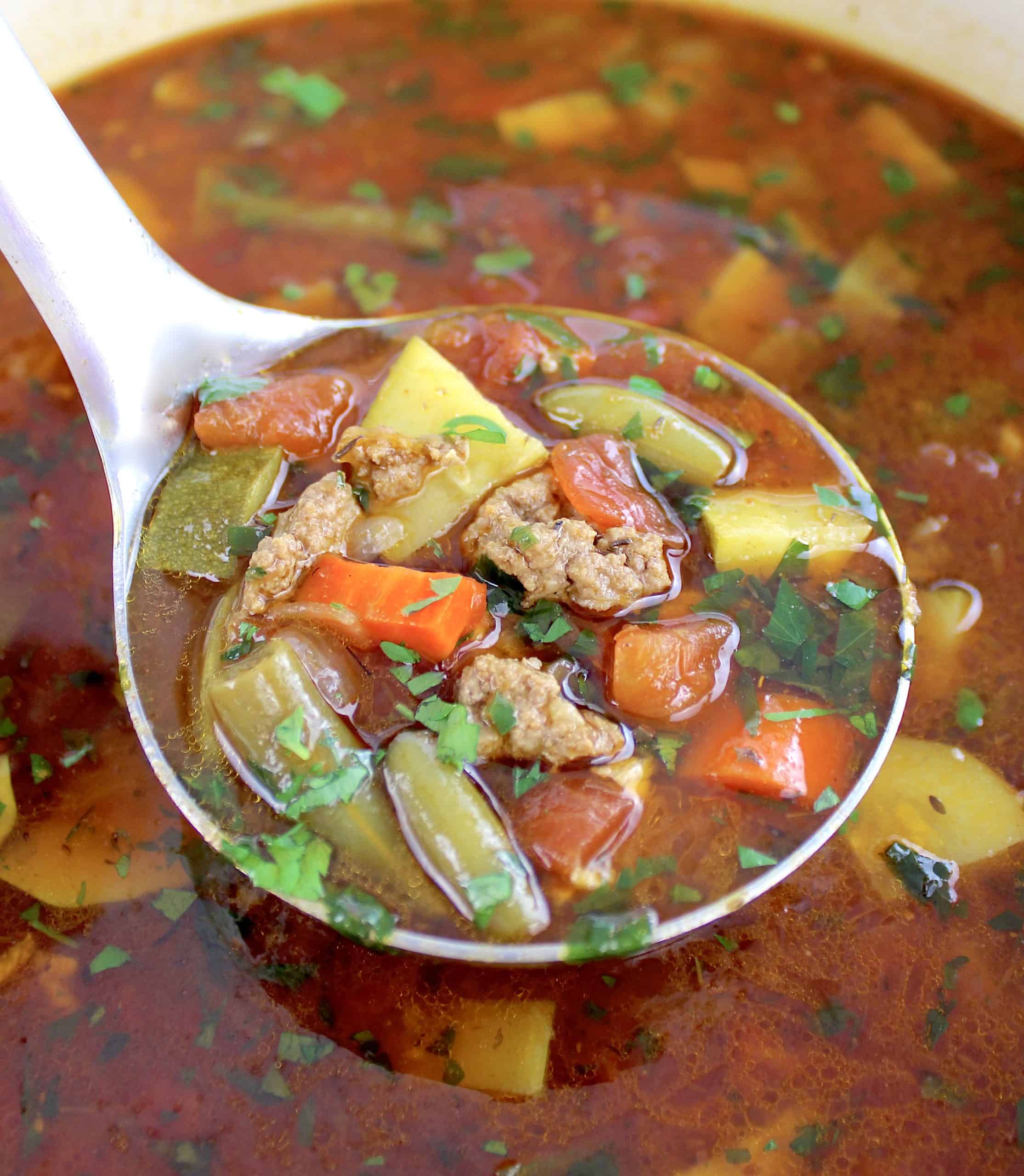 Vegetable Beef Soup being held up with ladle