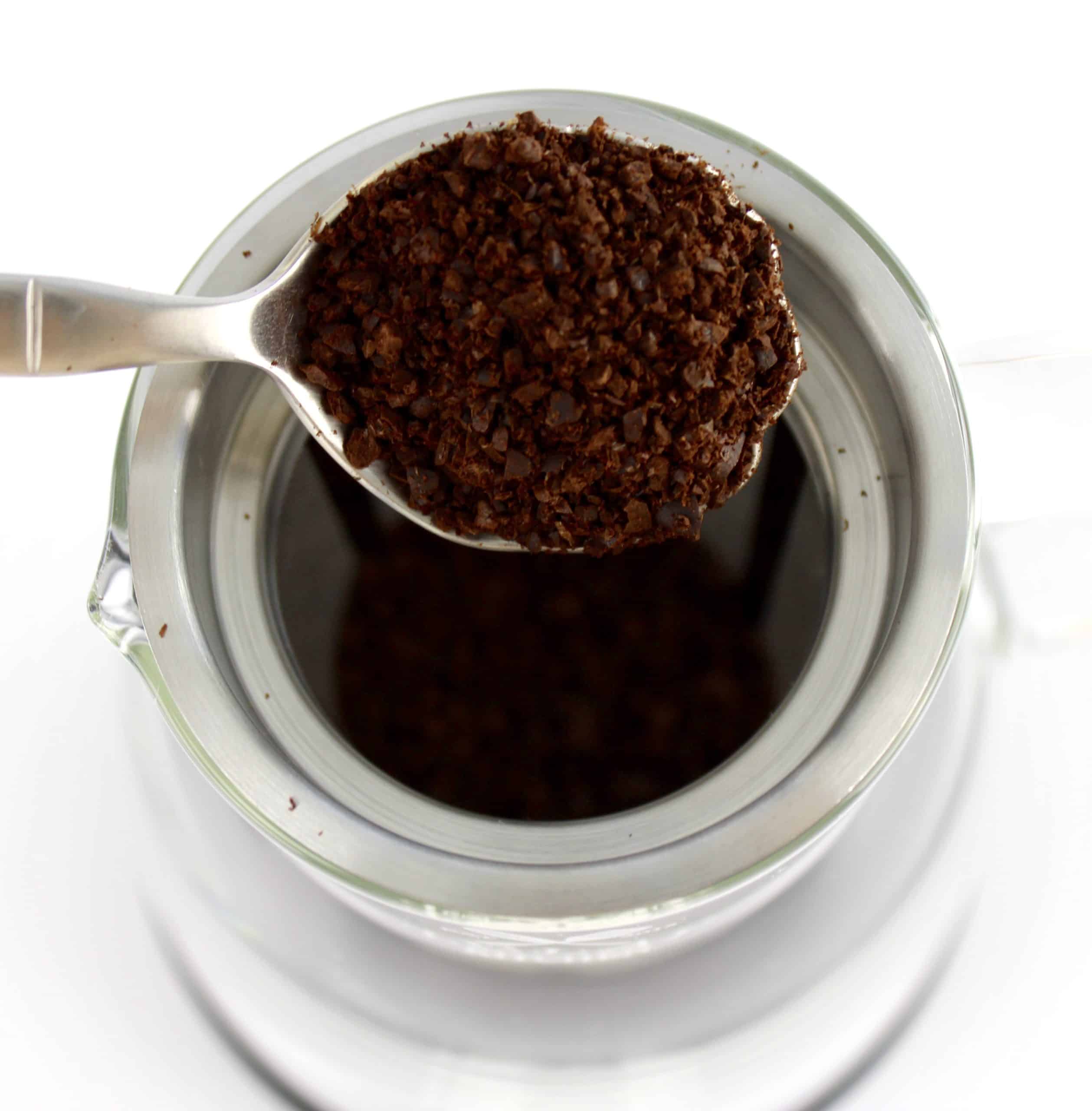 coffee grounds being spooned into coffee maker