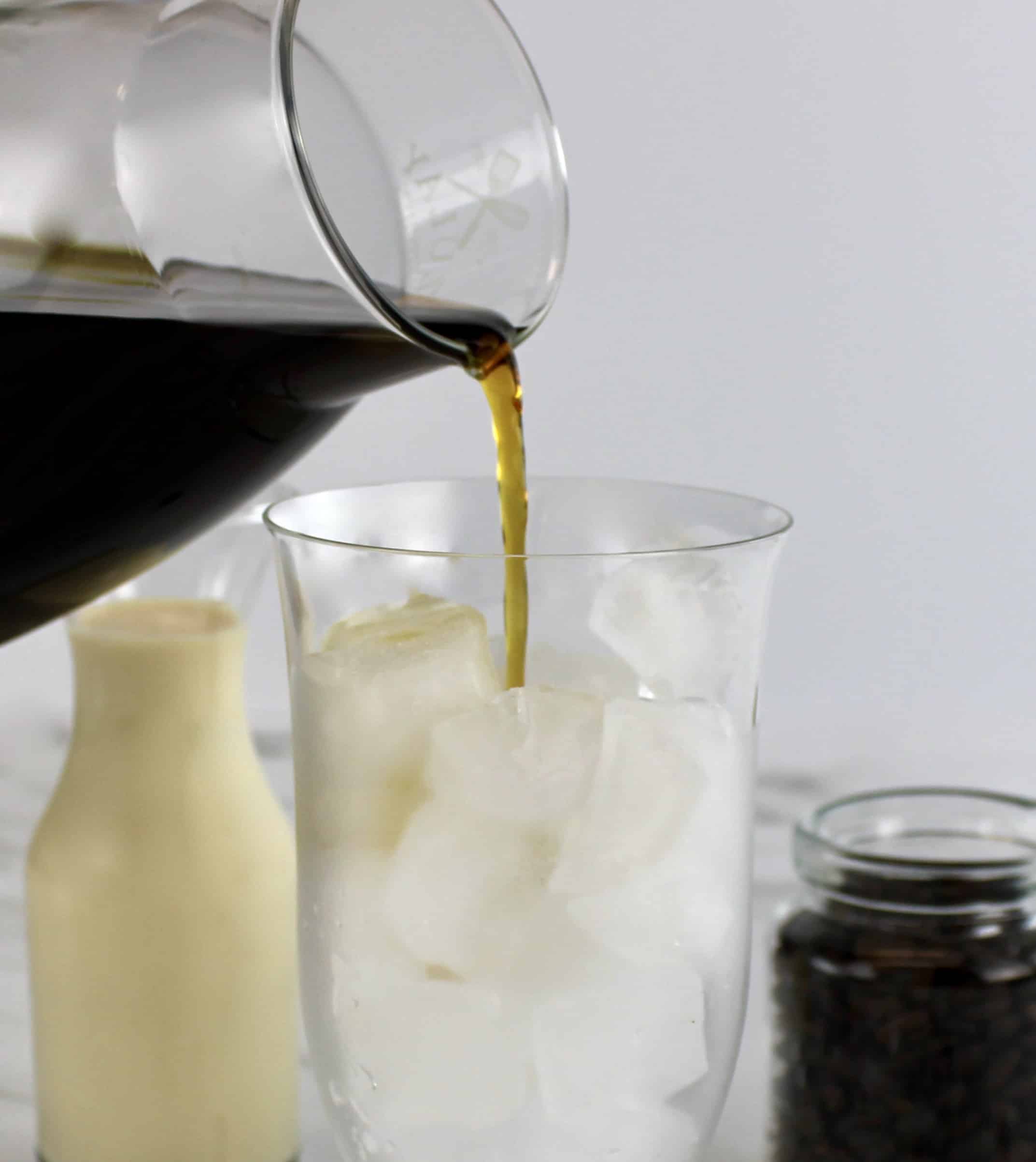 coffee being poured in glass over ice