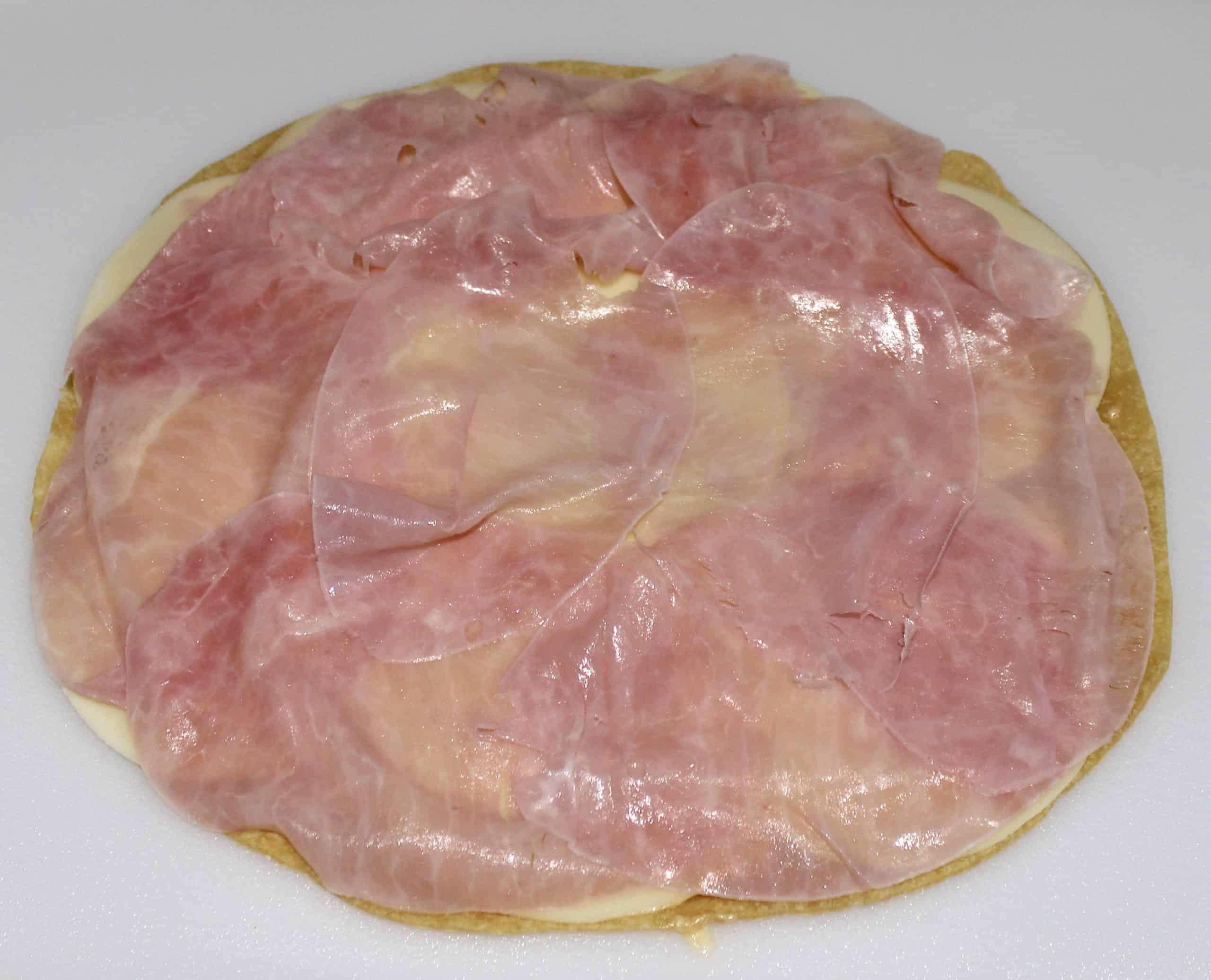 ham over tortilla on white cutting board