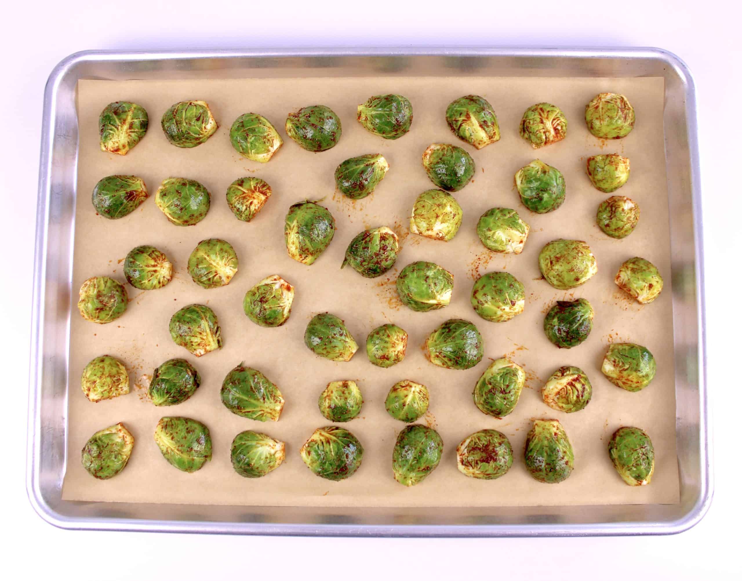 raw brussels sprouts with spices on parchment lined baking sheet
