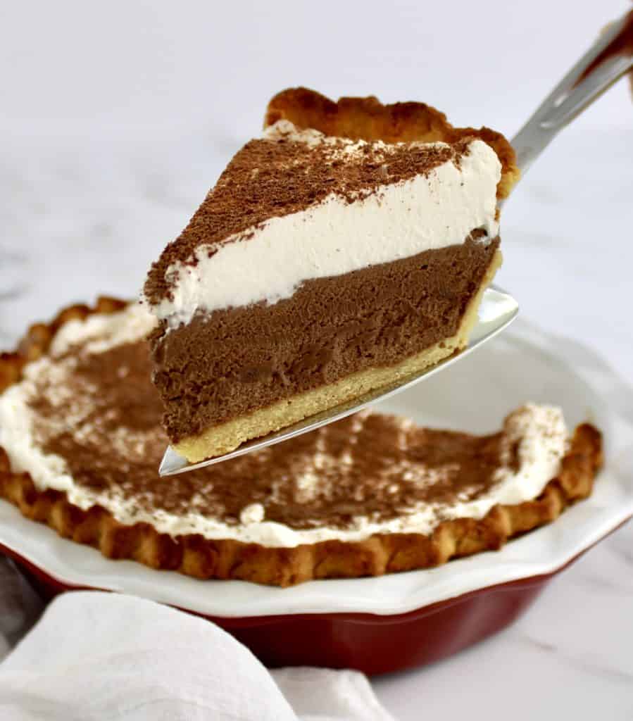 slice of french silk pie on pie server with whip cream on top