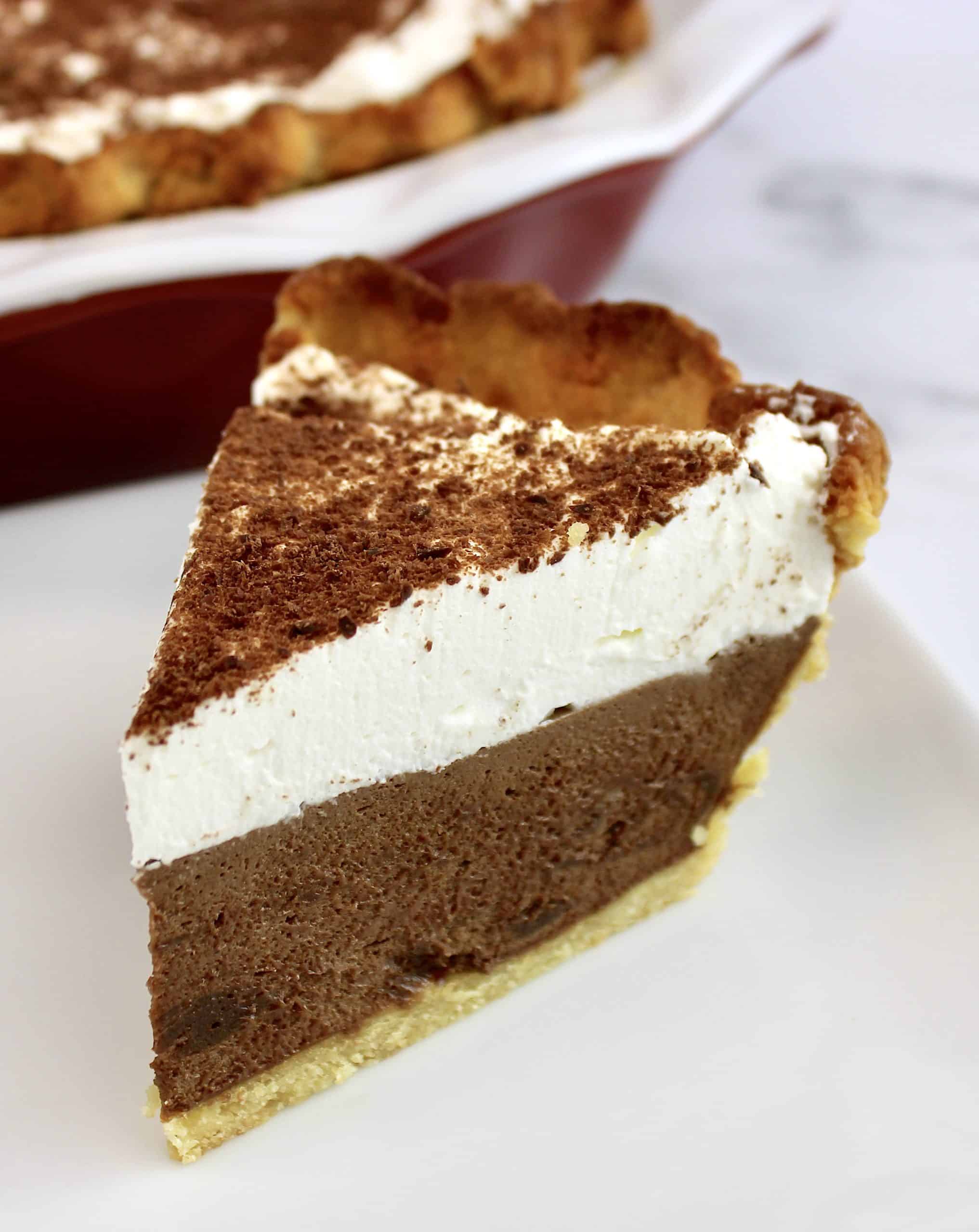 slice of french silk pie on pie server with whip cream on top on white plate