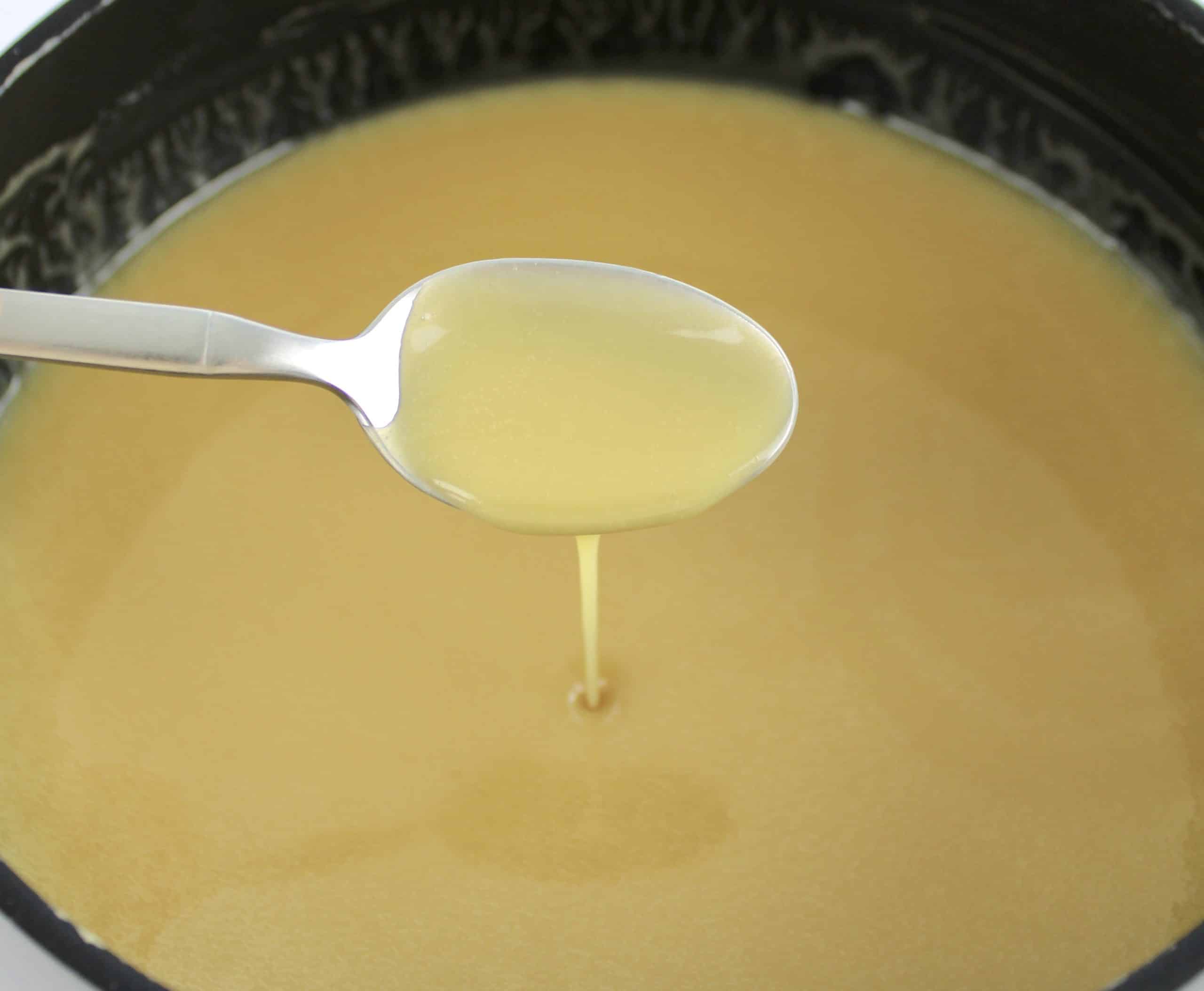 sweetened condensed milk in saucepan with spoon dripping some