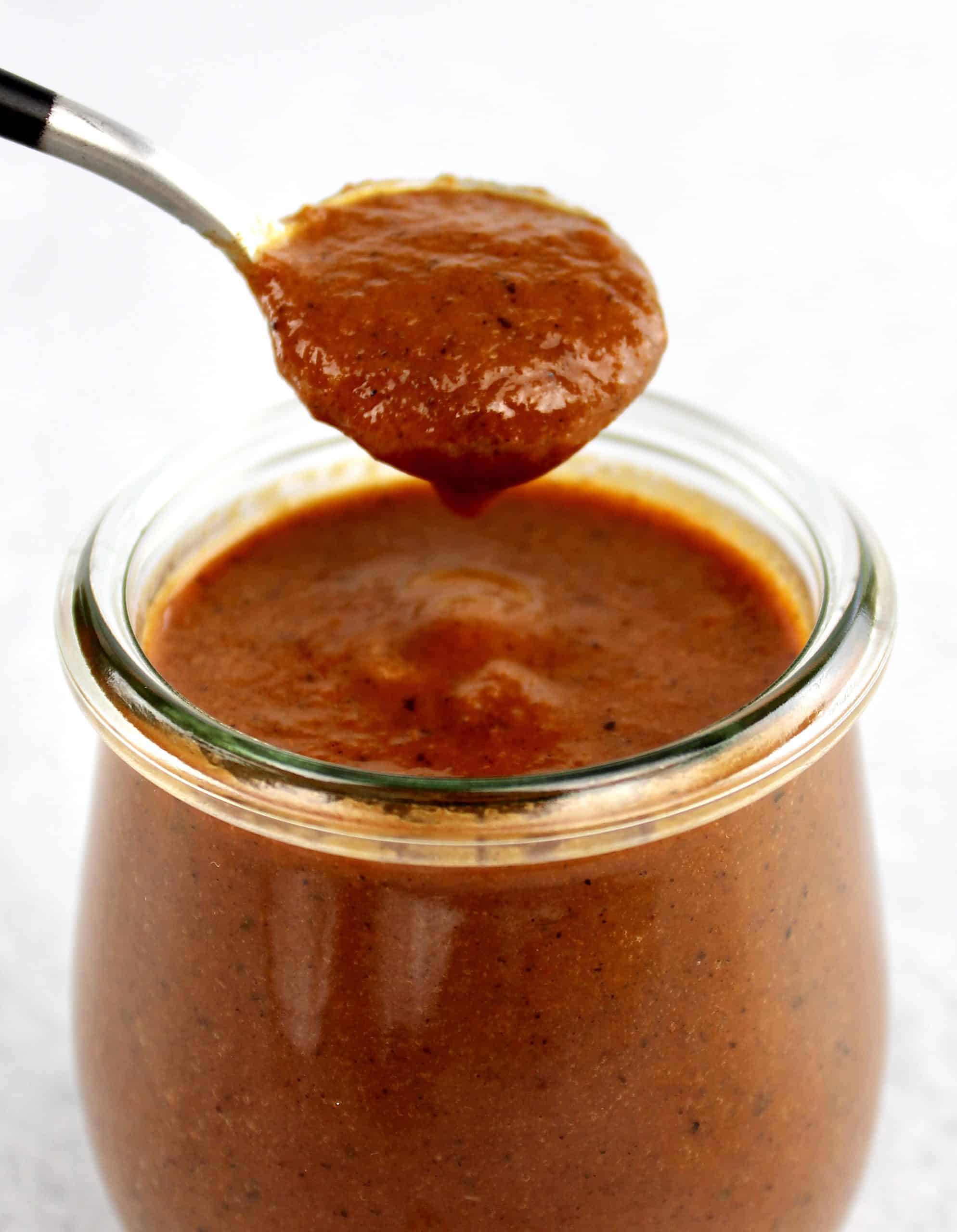 Keto Enchilada Sauce being spooned out of glass jar