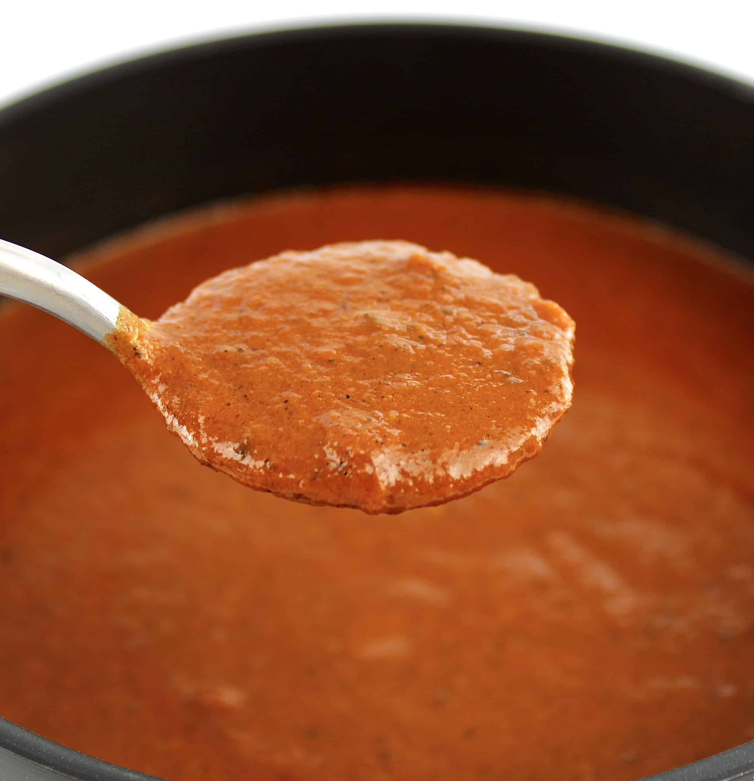 Keto Enchilada Sauce held up in spoon over saucepan
