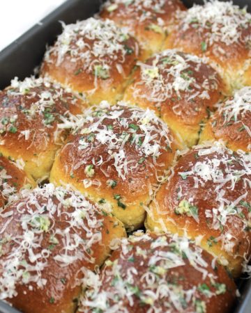 keto garlic rolls in pan with grated parmesan on top
