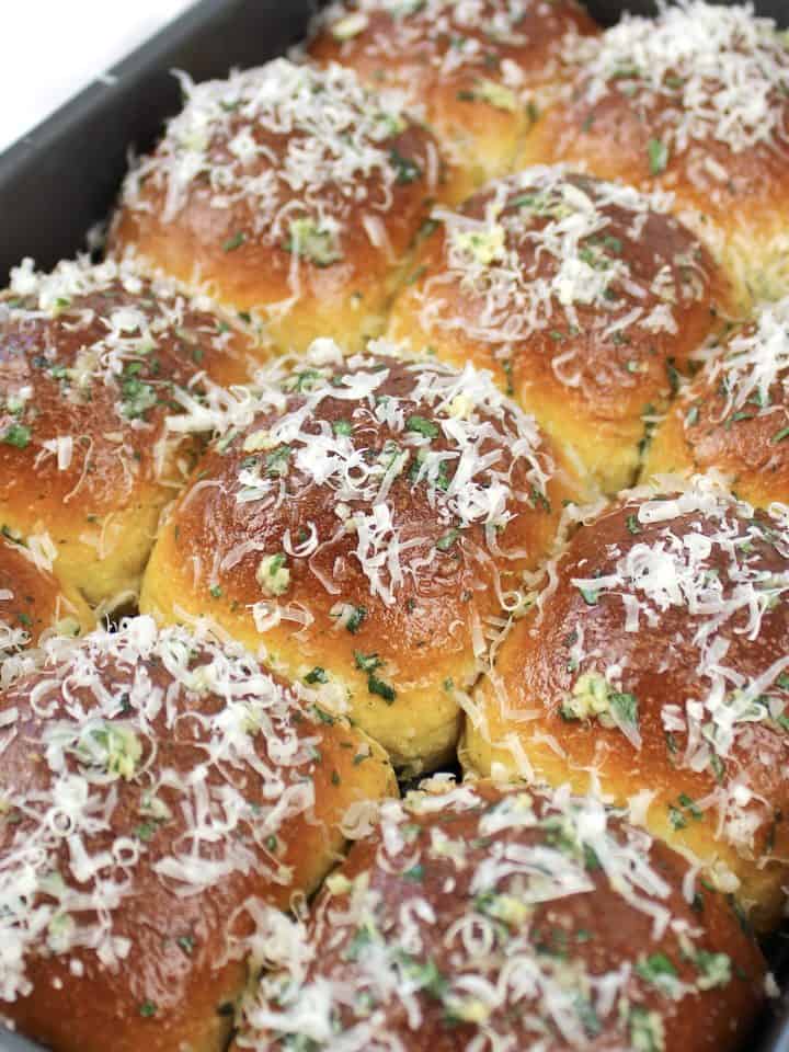 keto garlic rolls in pan with grated parmesan on top