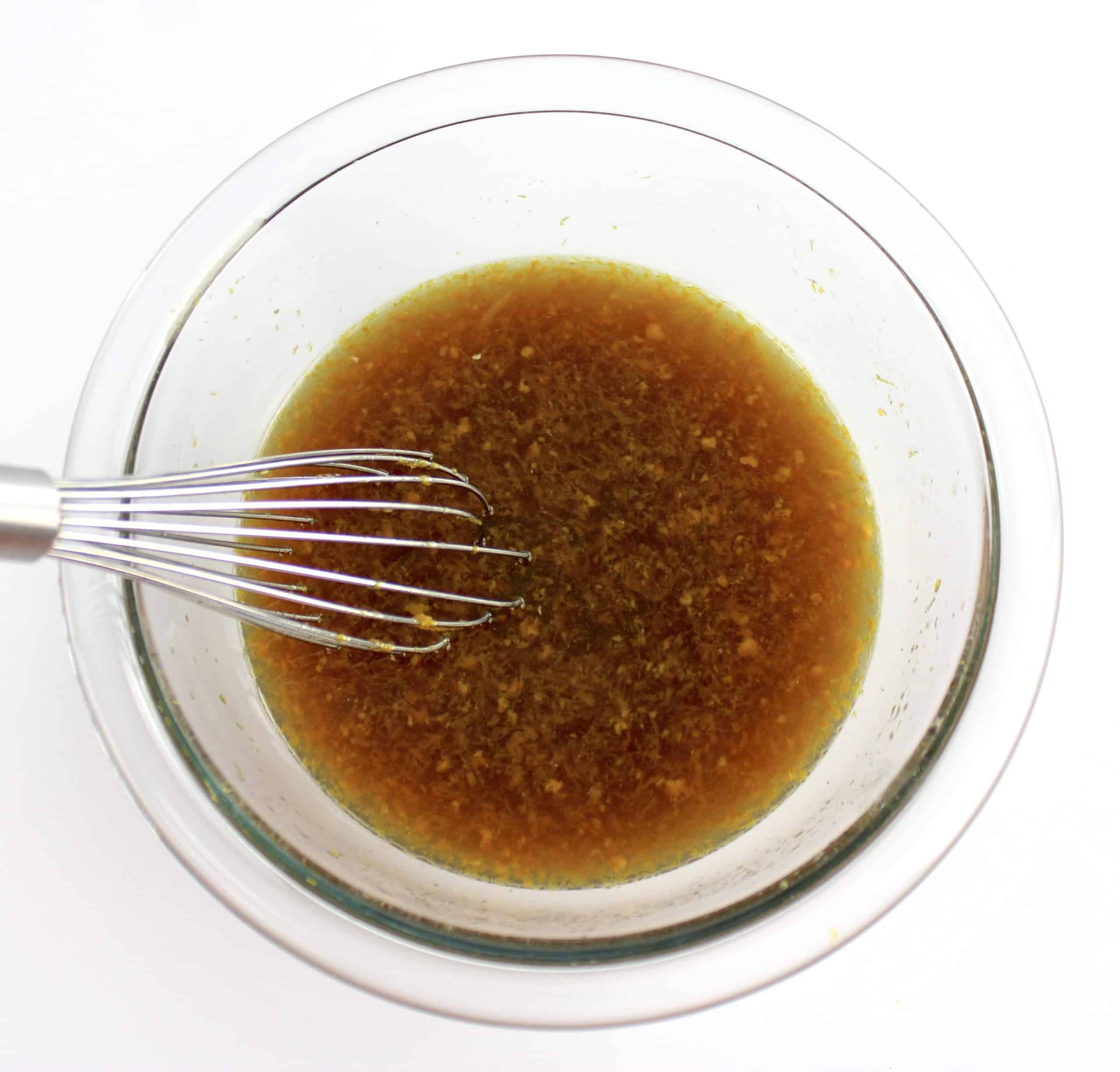 orange chicken sauce in glass bowl with whisk