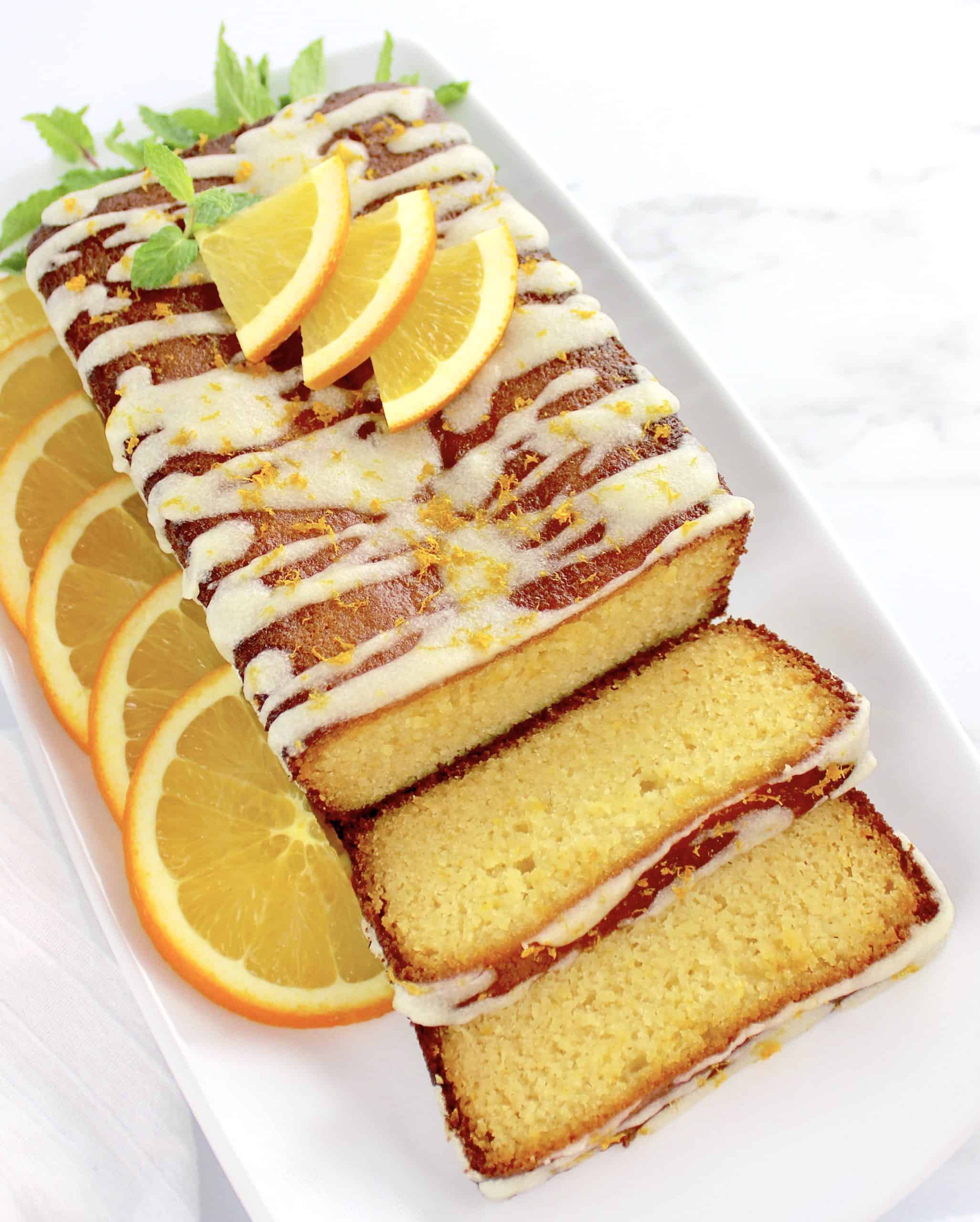 Keto Orange Pound Cake sliced on white plate with oranges