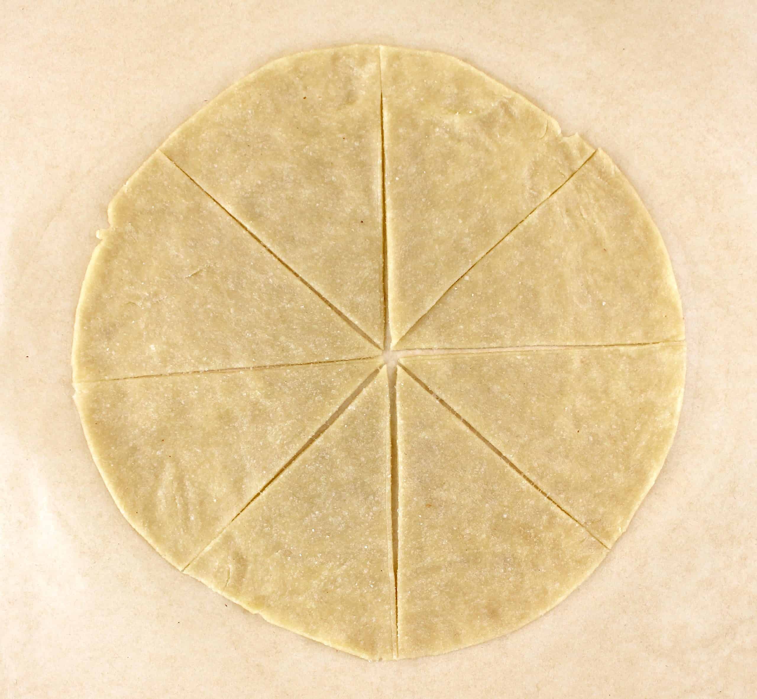 tortilla rolled out on parchment slice in 8 wedges